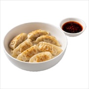 Pan-fried gyoza in a white bowl with a chilli dipping sauce alongside — iDoCatering buffet