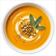 Pumpkin soup swirled with cream and topped with pumpkin seeds and sage in a white bowl — iDoCatering buffet