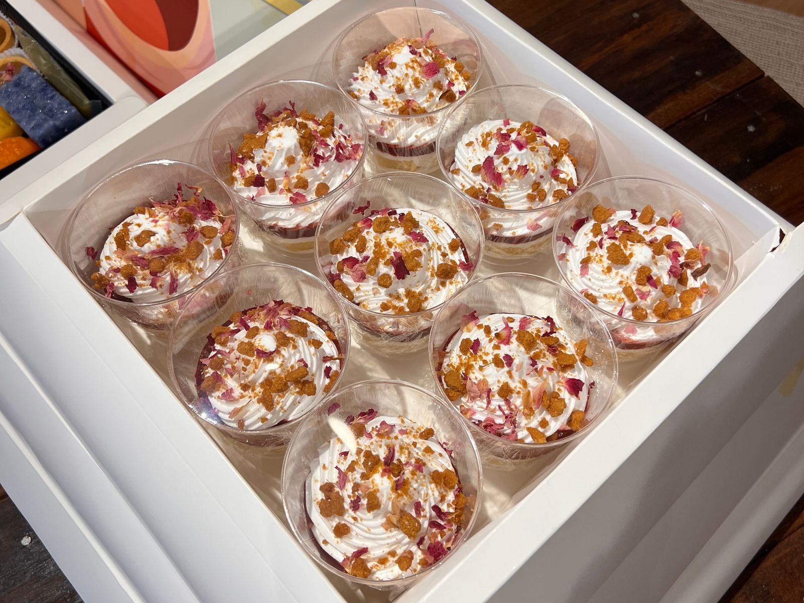 Nine trifle cups topped with cream, rose petals and biscuit crumble — iDoCatering Pyramid Dessert Box