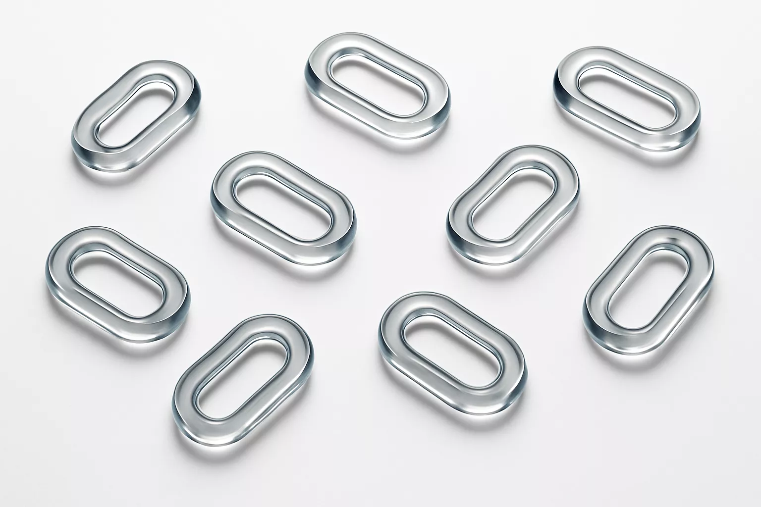 Eight transparent oval-shaped glass rings arranged on a white surface.