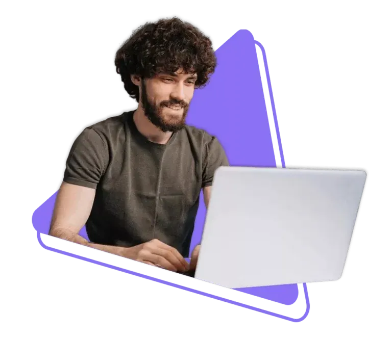 Bearded man with curly hair smiling while using a laptop with purple geometric background shape.