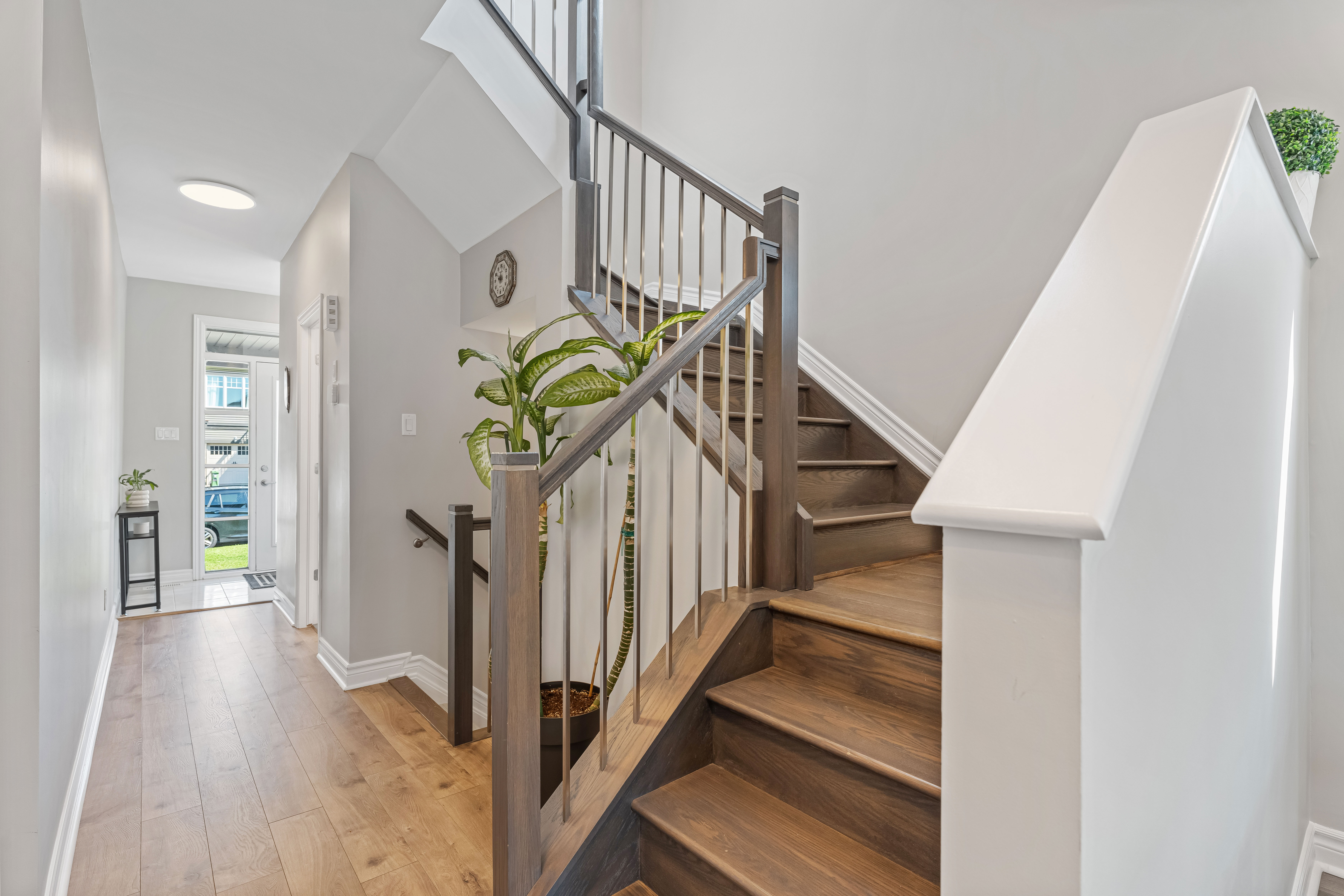 An entry hall with a staircase and the front door beyond