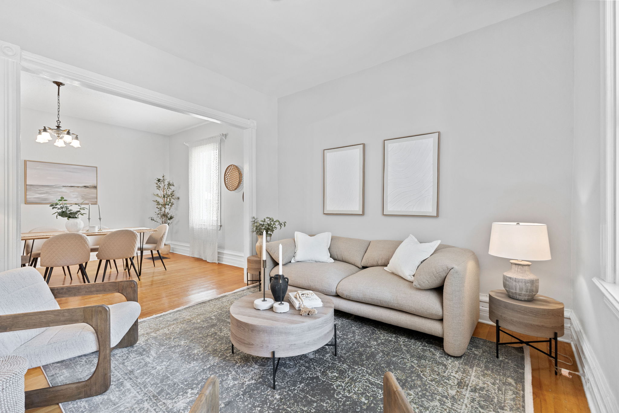 A living room opening into the dining room, with daylight through the windows