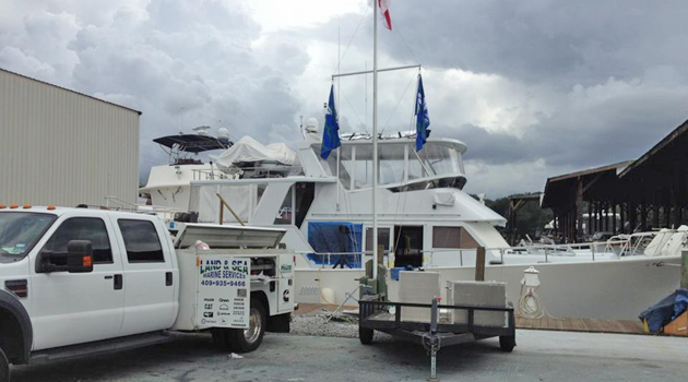 Land & Sea service truck parked beside a yacht