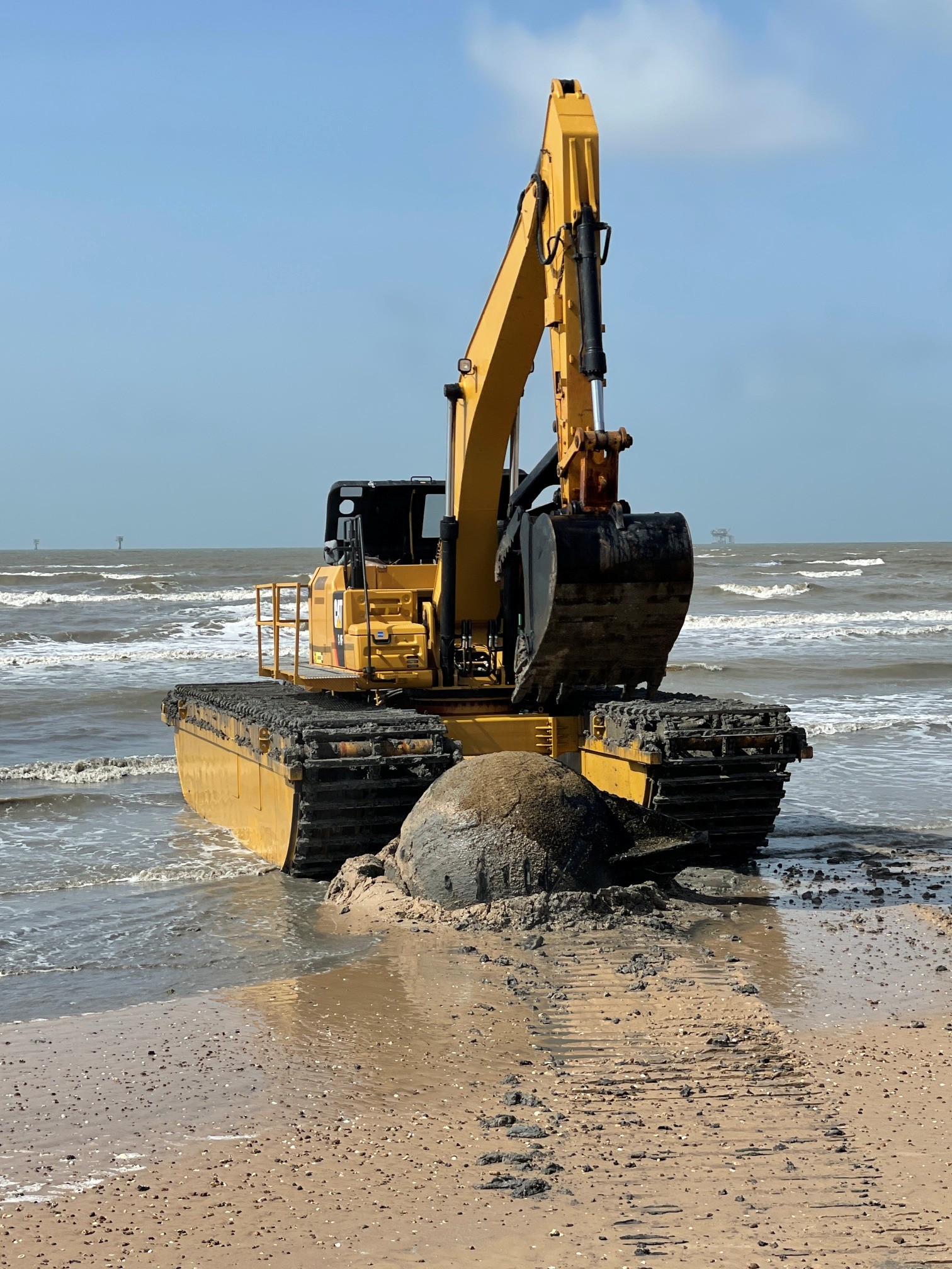 Amphibious excavator working in the surf to recover a vessel