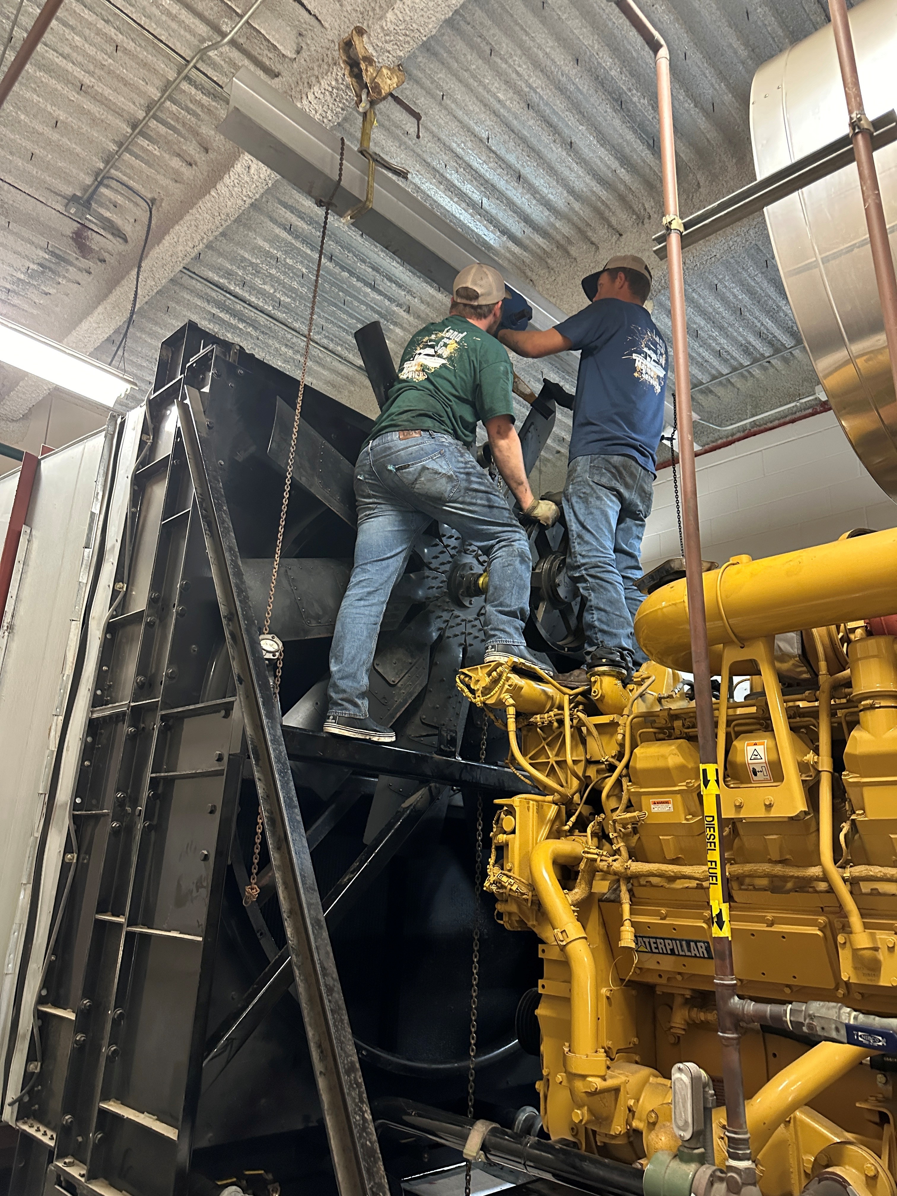 Technicians repairing a large yellow diesel generator
