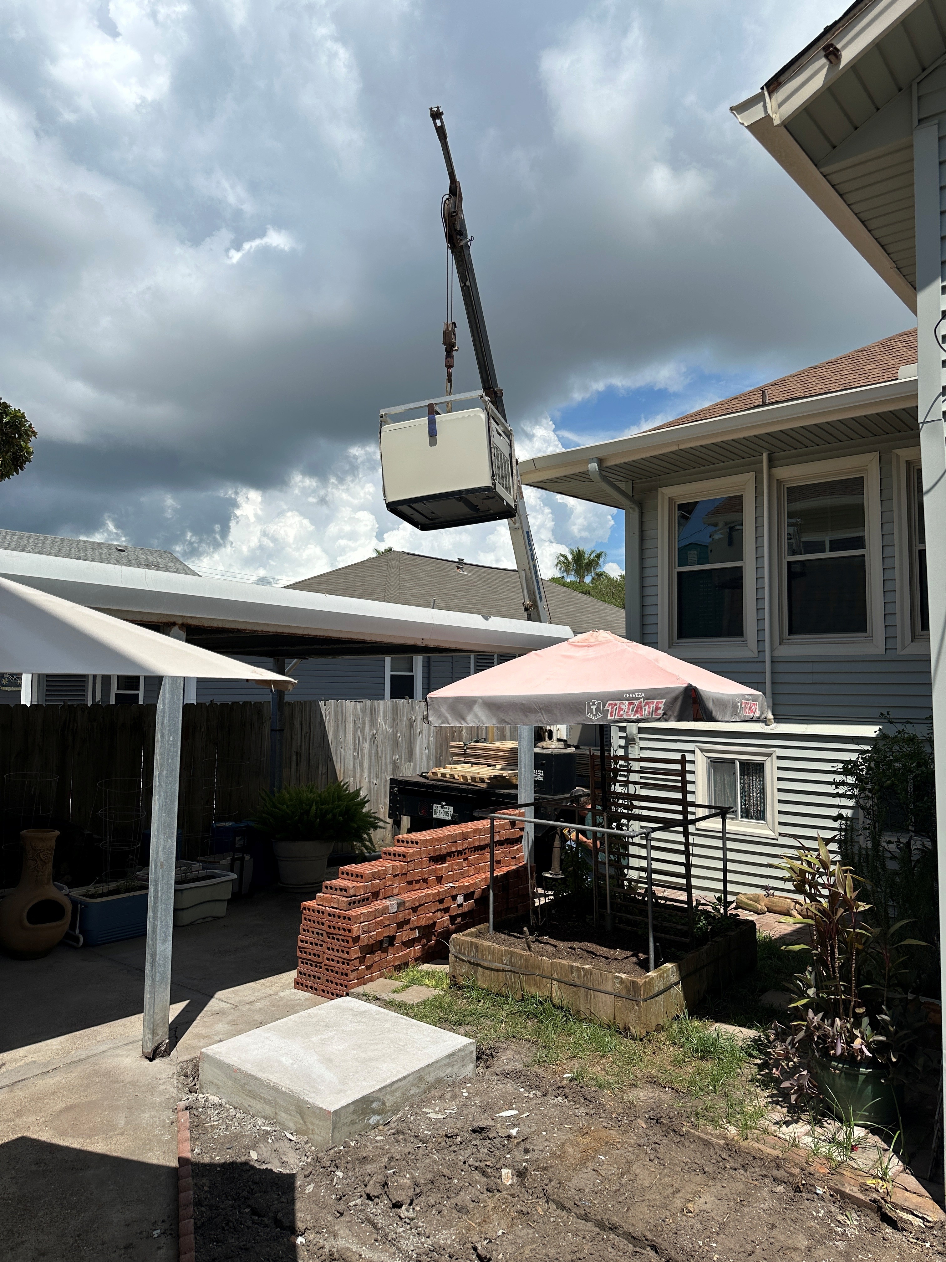 Crane lifting a generator beside an elevated home
