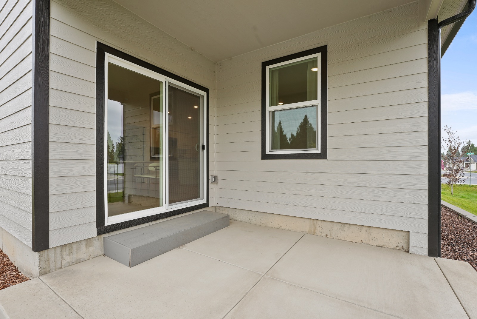 The covered back patio: a poured concrete slab under deep eaves, with a sliding glass door to the living room.