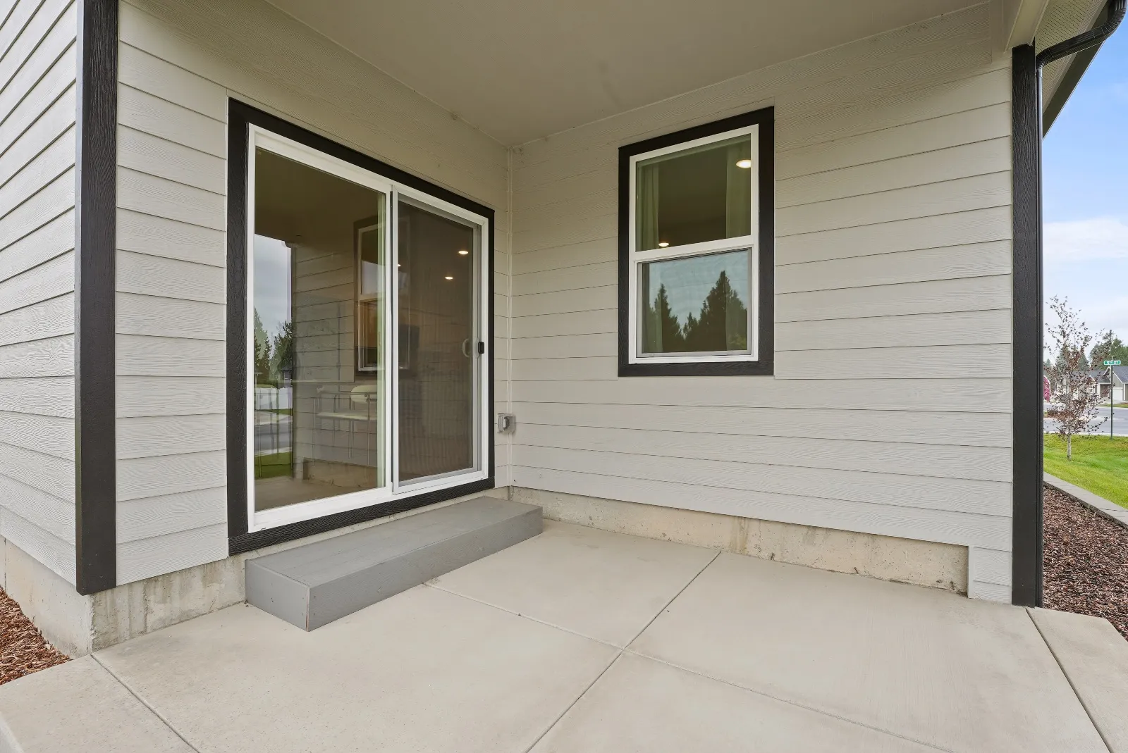 The covered back patio: a poured concrete slab under deep eaves, with a sliding glass door to the living room.