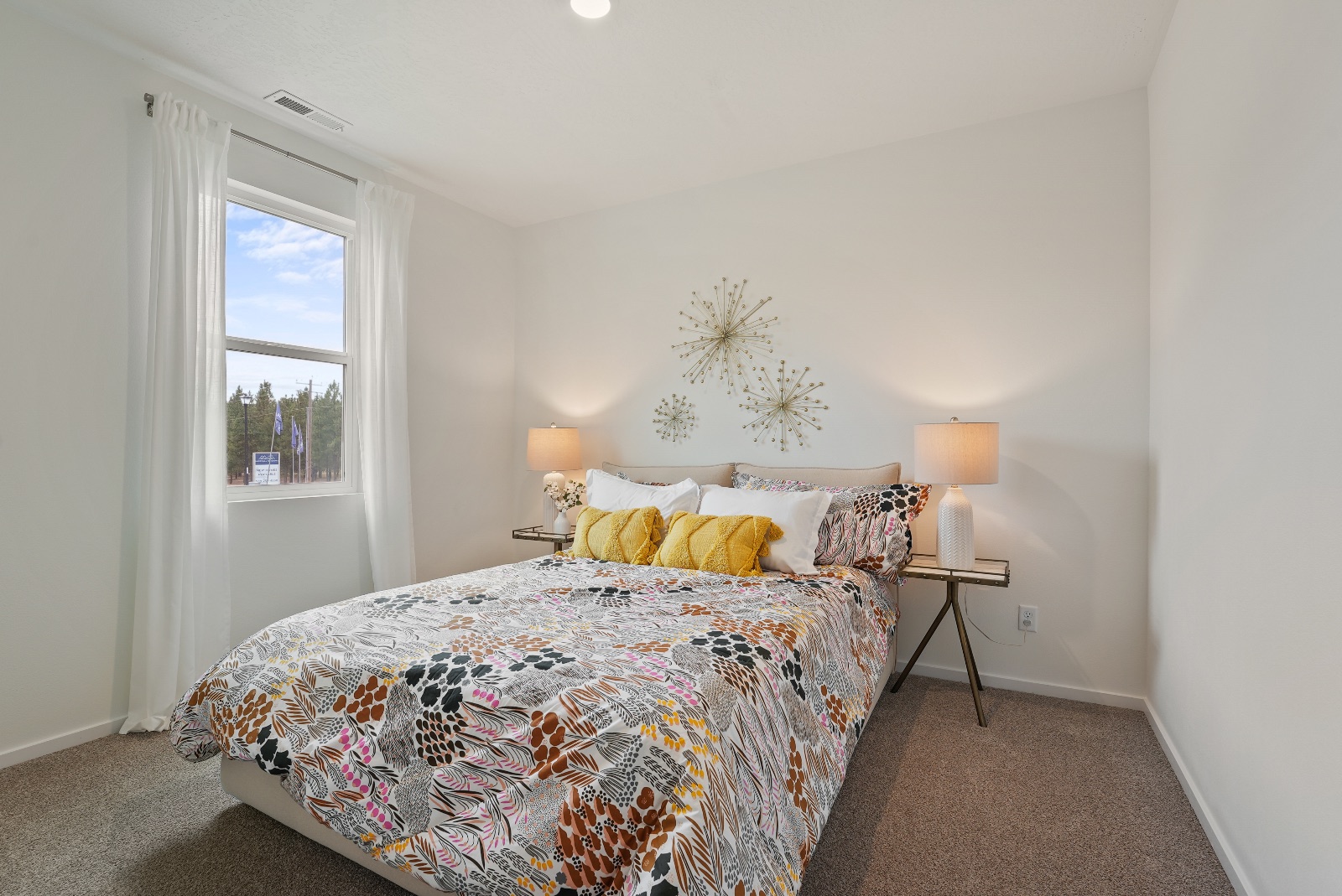 Another secondary bedroom, carpeted, with a window onto the pines at the edge of the neighborhood.