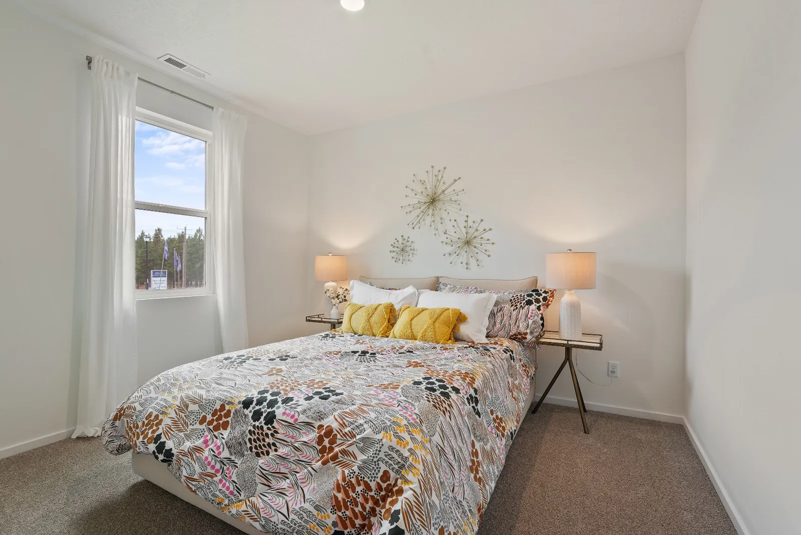 Another secondary bedroom, carpeted, with a window onto the pines at the edge of the neighborhood.