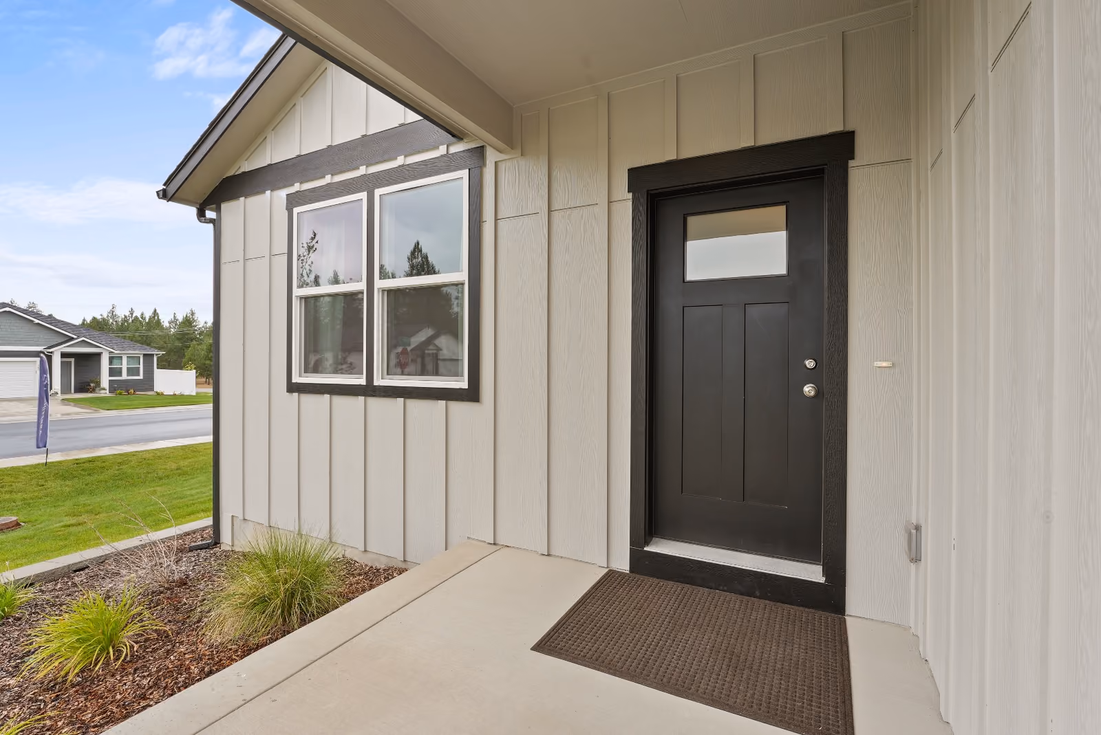 The covered front entry with a charcoal craftsman door and a window onto the porch.