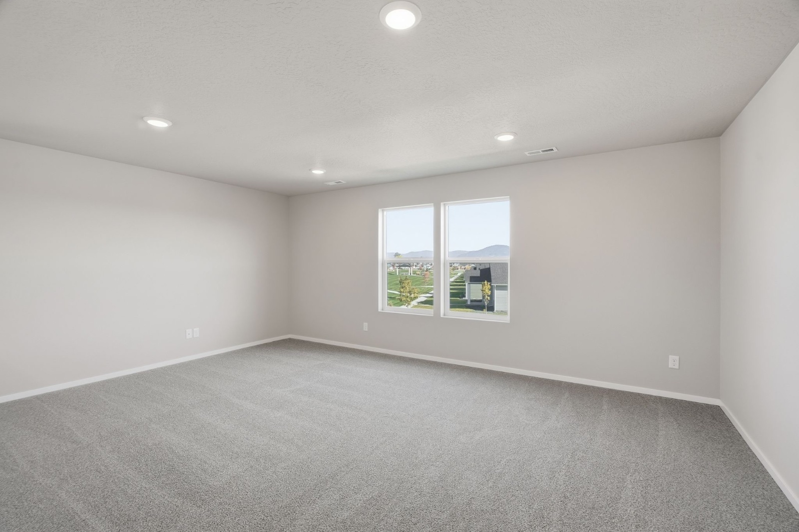 A carpeted secondary bedroom in a Phoenix plan home, with paired windows facing the street.