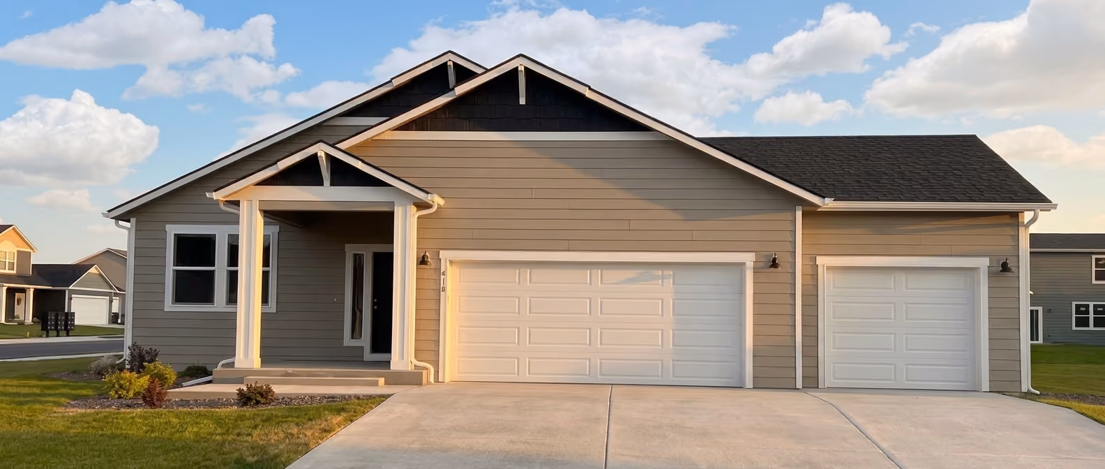 The front of 418 N Arcadia Ave at golden hour: single-level craftsman elevation in warm greige lap siding with white trim, a gabled entry porch, and a three-car garage off the wide driveway.