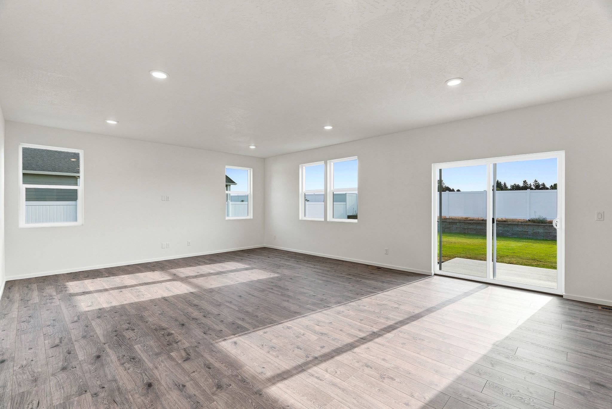 A Clearwater plan living room in luxury plank flooring, with windows on two walls and a slider to the back yard.