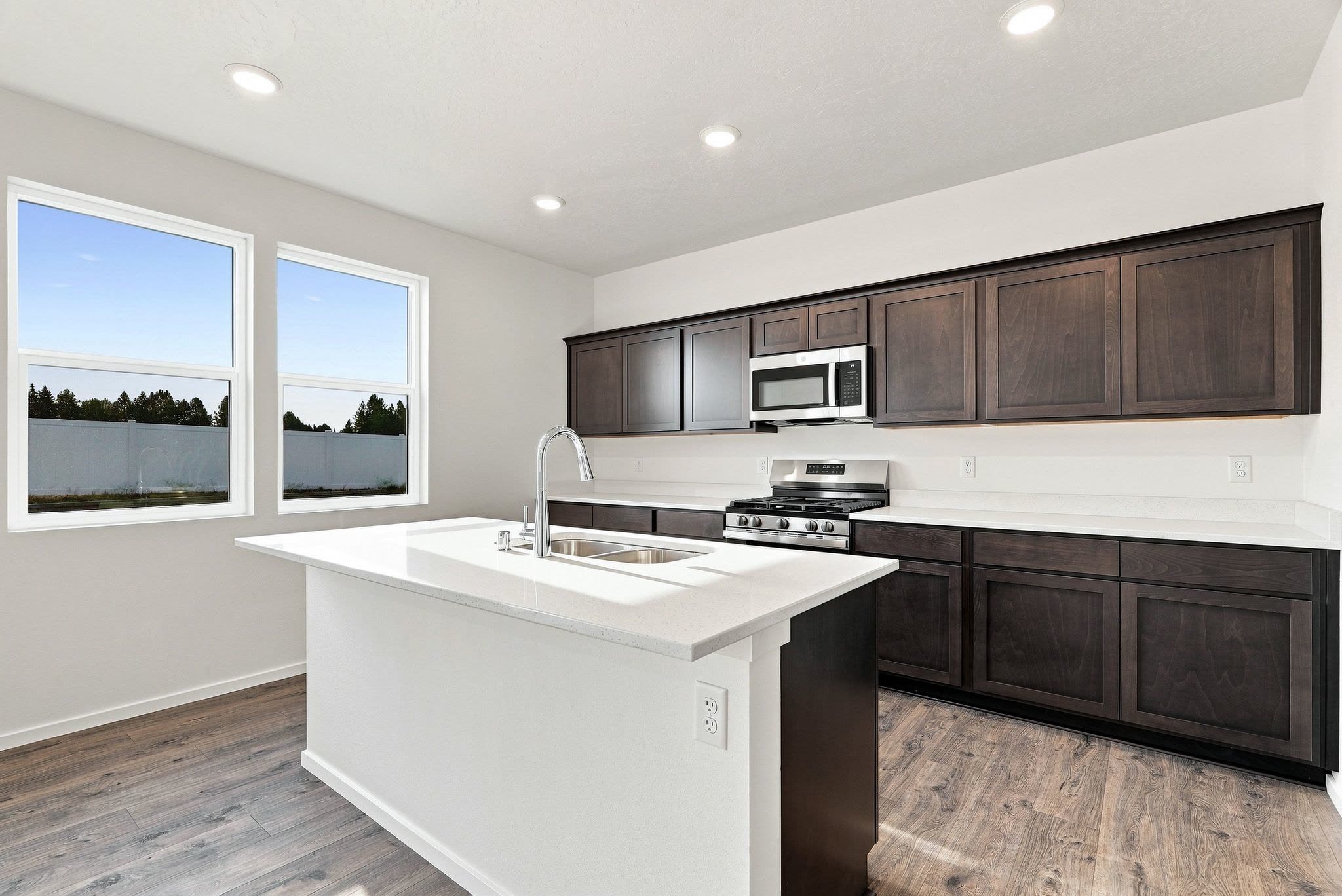 A Clearwater plan kitchen: dark shaker cabinetry, quartz counters, a stainless gas range, and an island with a double undermount sink.