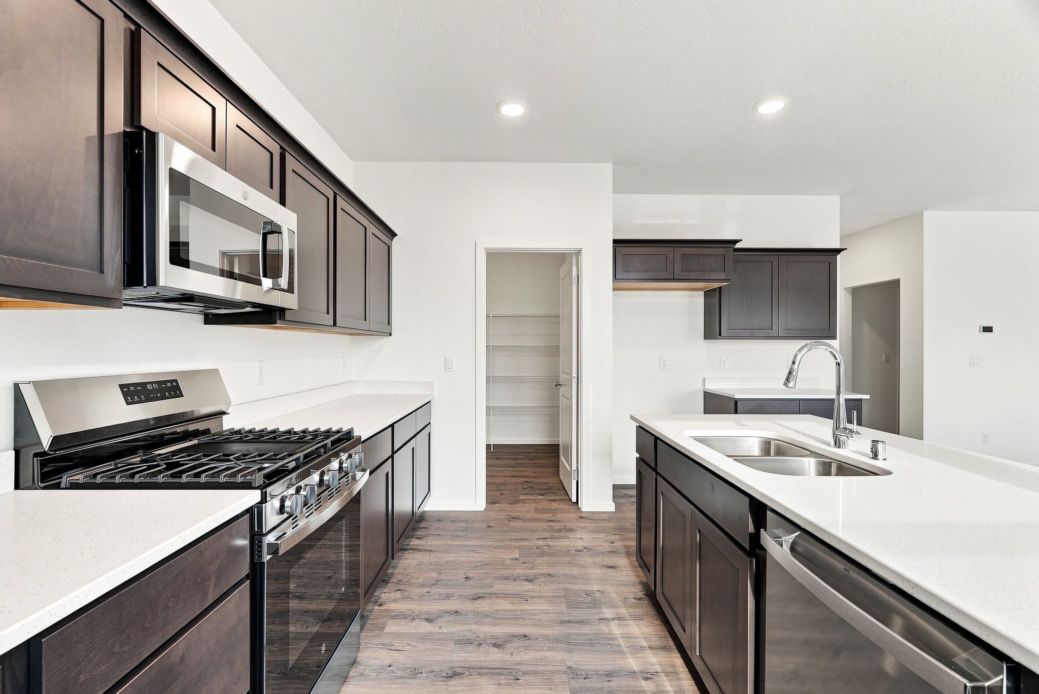 A Clearwater plan kitchen from the range wall, looking through to the walk-in pantry, shelved on three walls.