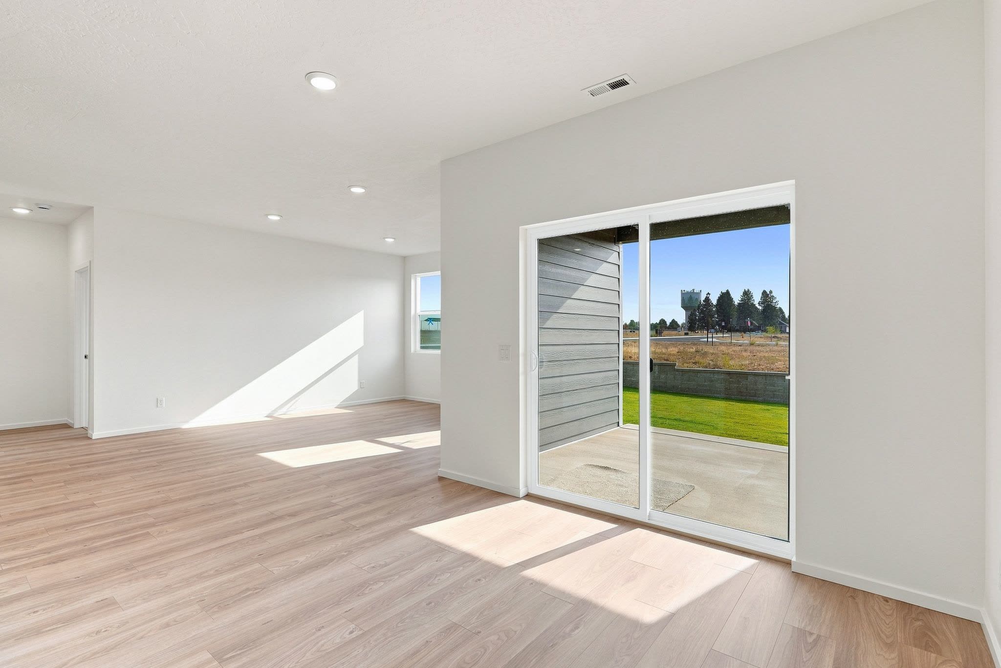 The living area with a slider out to the covered patio and open ground past the back fence.