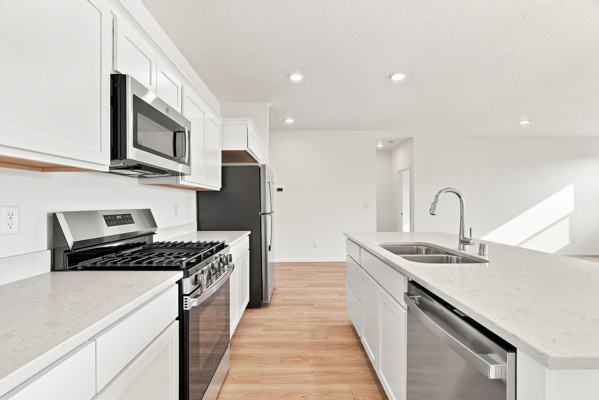 The kitchen along the range wall, with the island sink and dishwasher opposite and the hall beyond.
