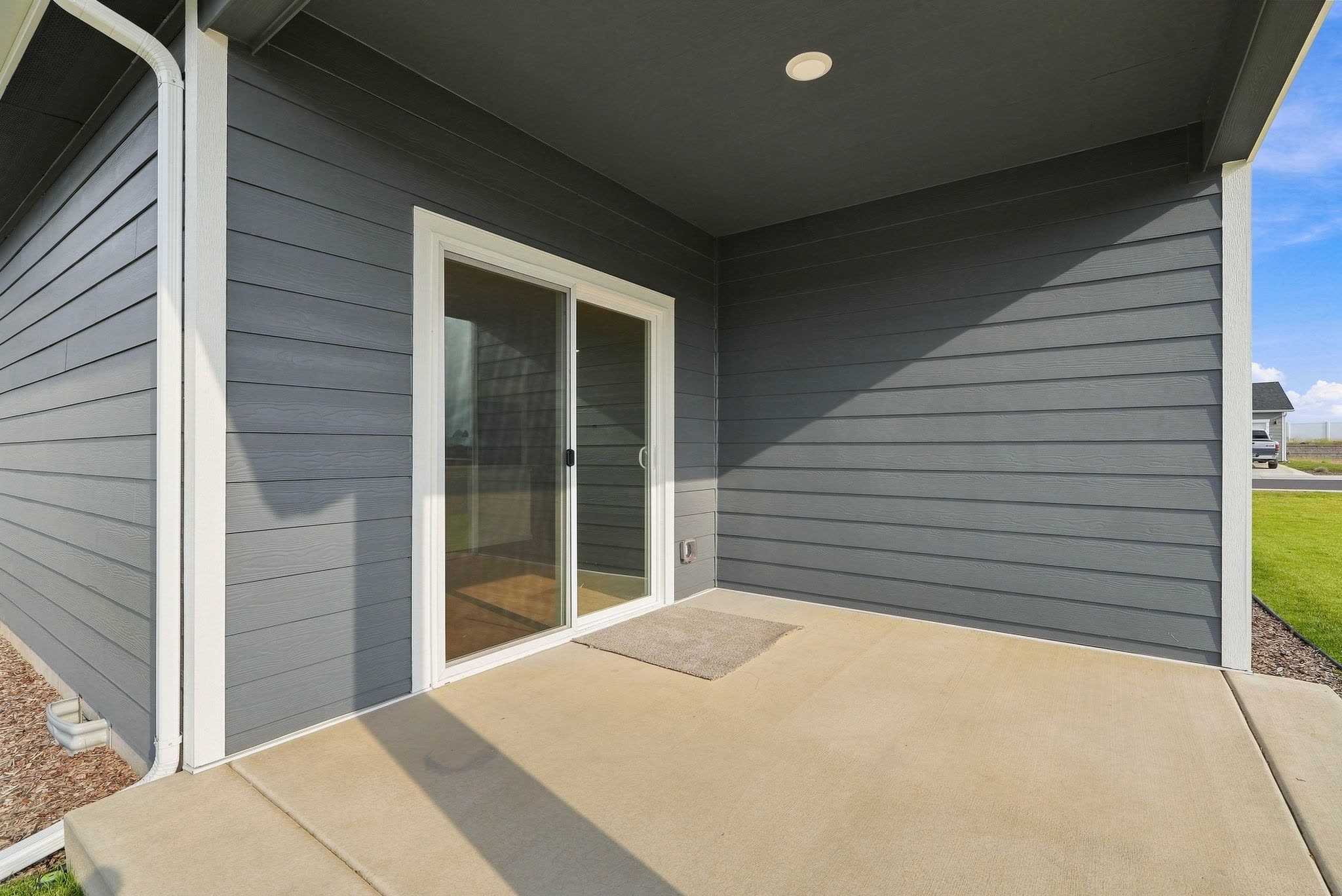 The covered back patio, a poured concrete slab under deep eaves off the living-room slider.