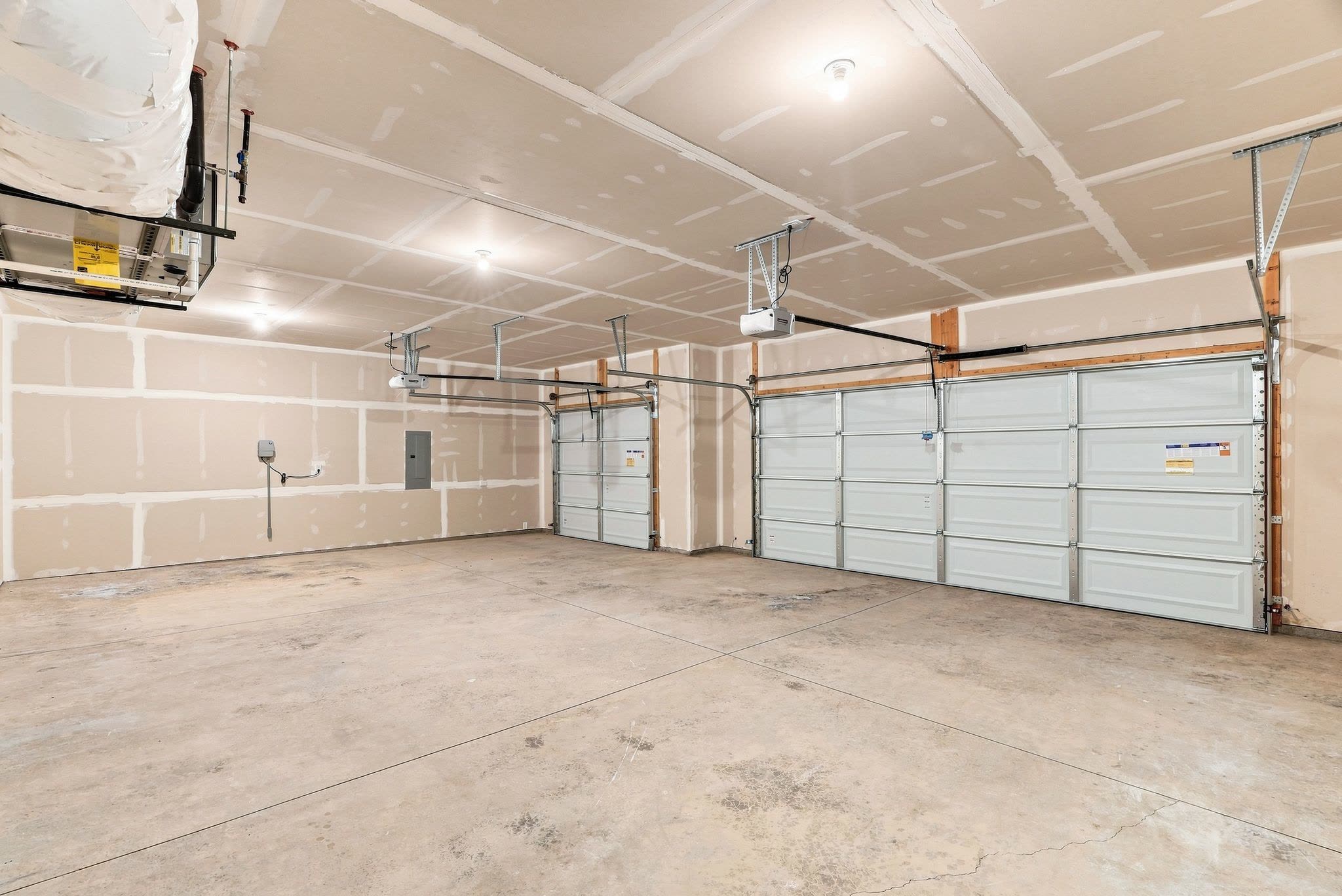 The three-car garage, drywalled, with openers fitted to both doors.
