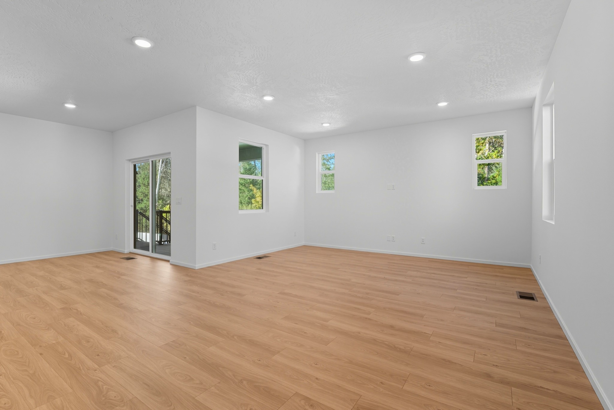 The Clark Fork plan: the great room in wood-look plank flooring, with a slider out to the deck and windows to the trees.