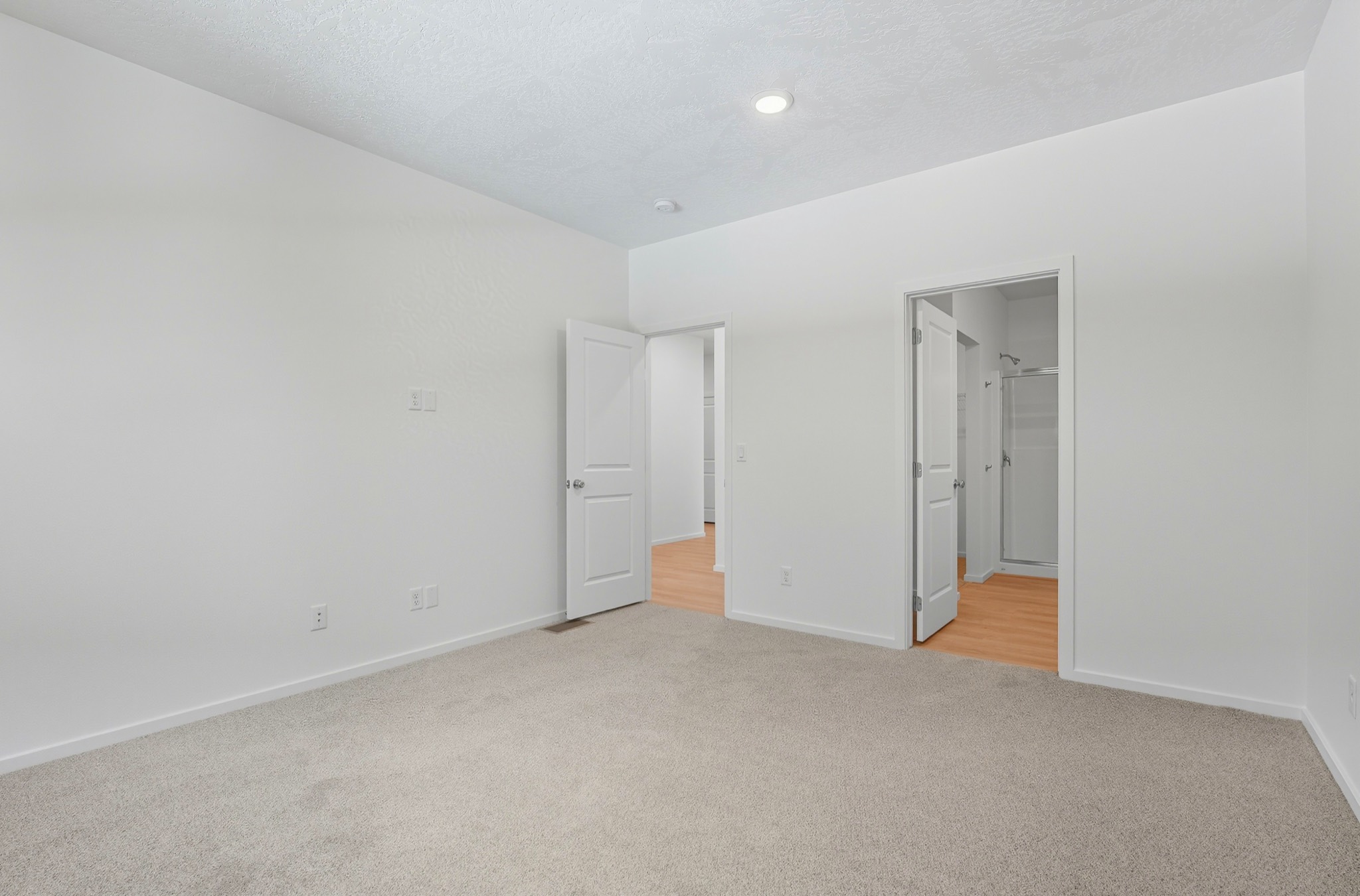 The Clark Fork plan: the carpeted primary bedroom, with doors through to the walk-in closet and the ensuite shower.