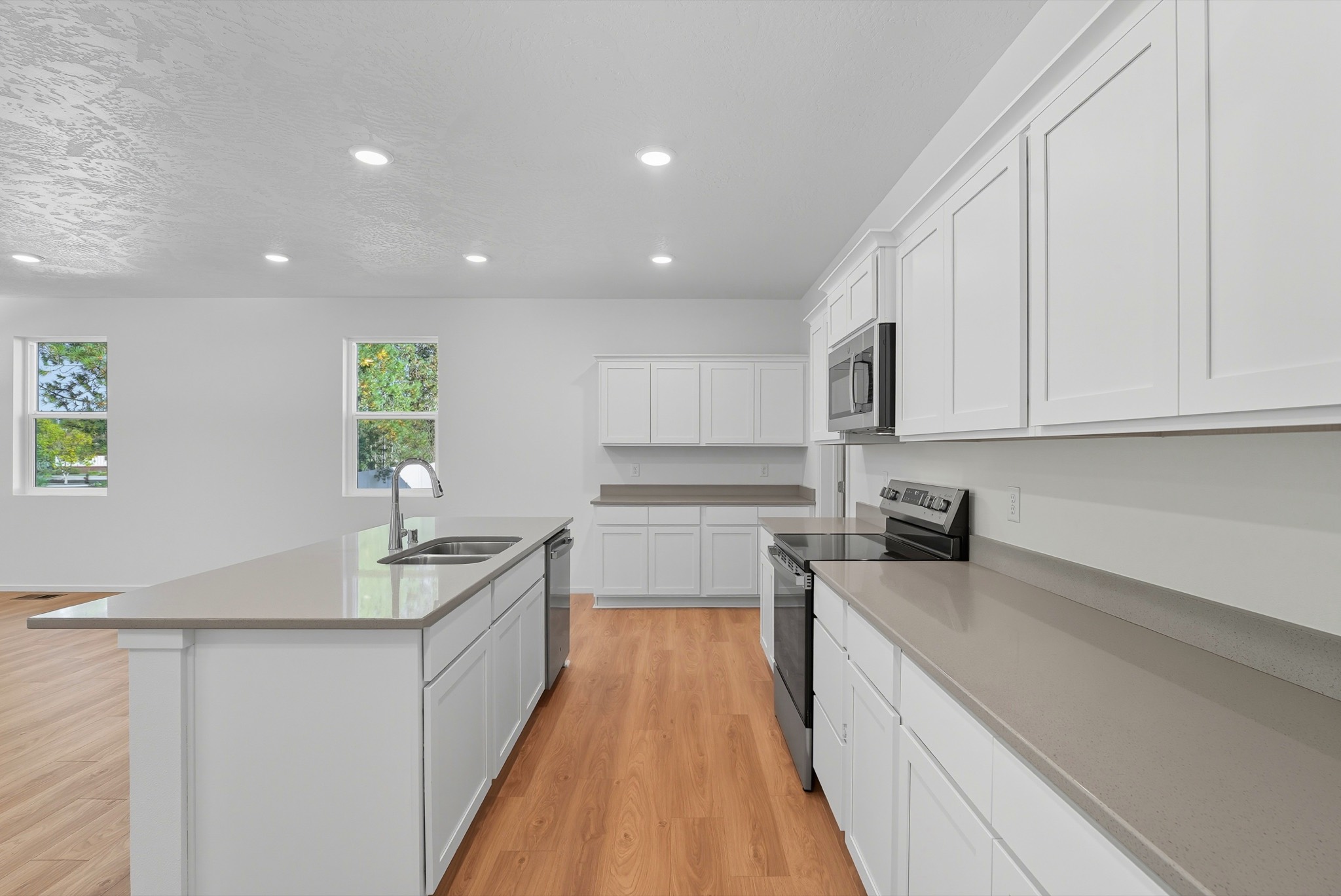 The Clark Fork plan: the kitchen in white shaker cabinetry with a grey quartz island, stainless range and microwave.