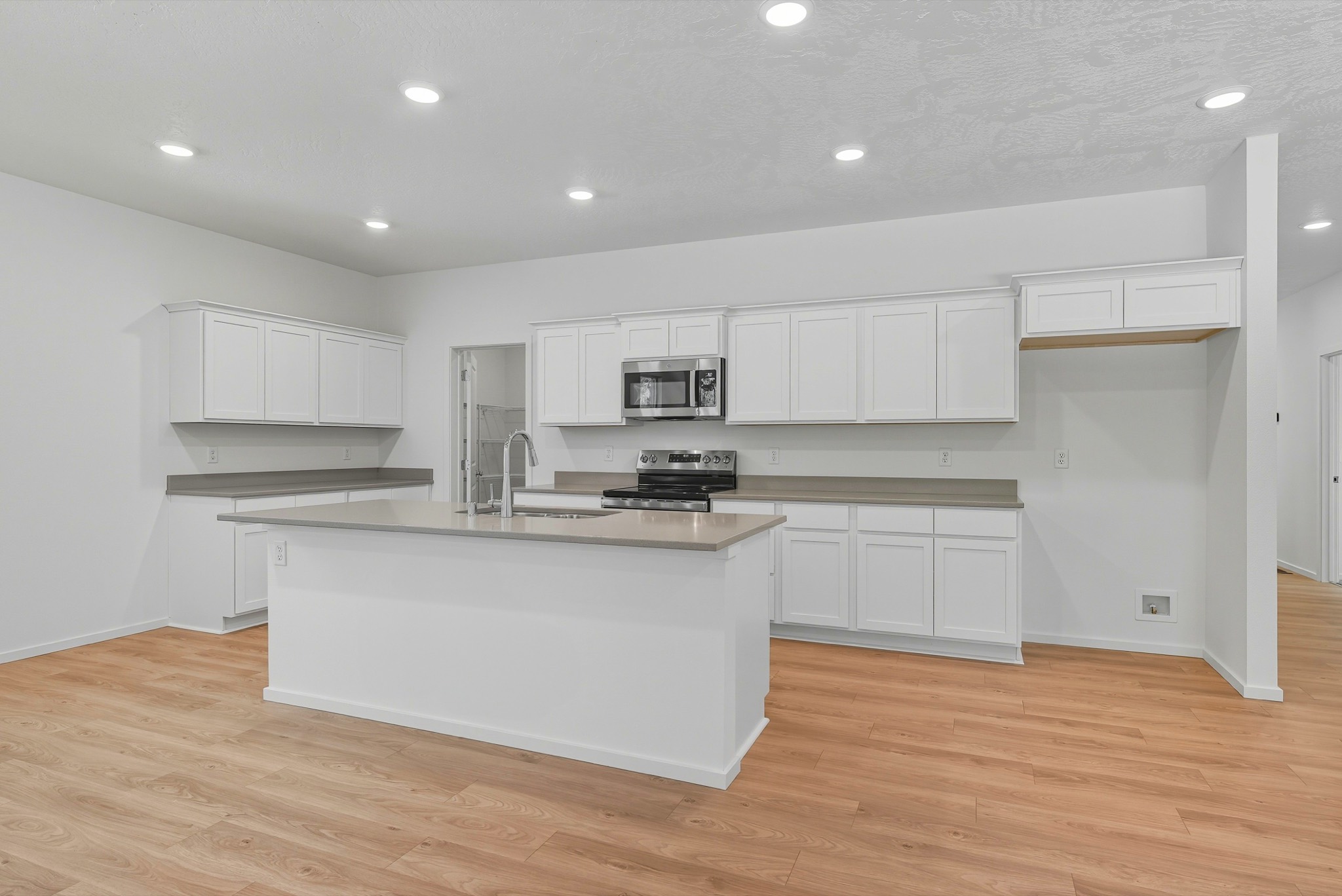 The Clark Fork plan: the kitchen looking across the island to full-height cabinetry and the range wall.
