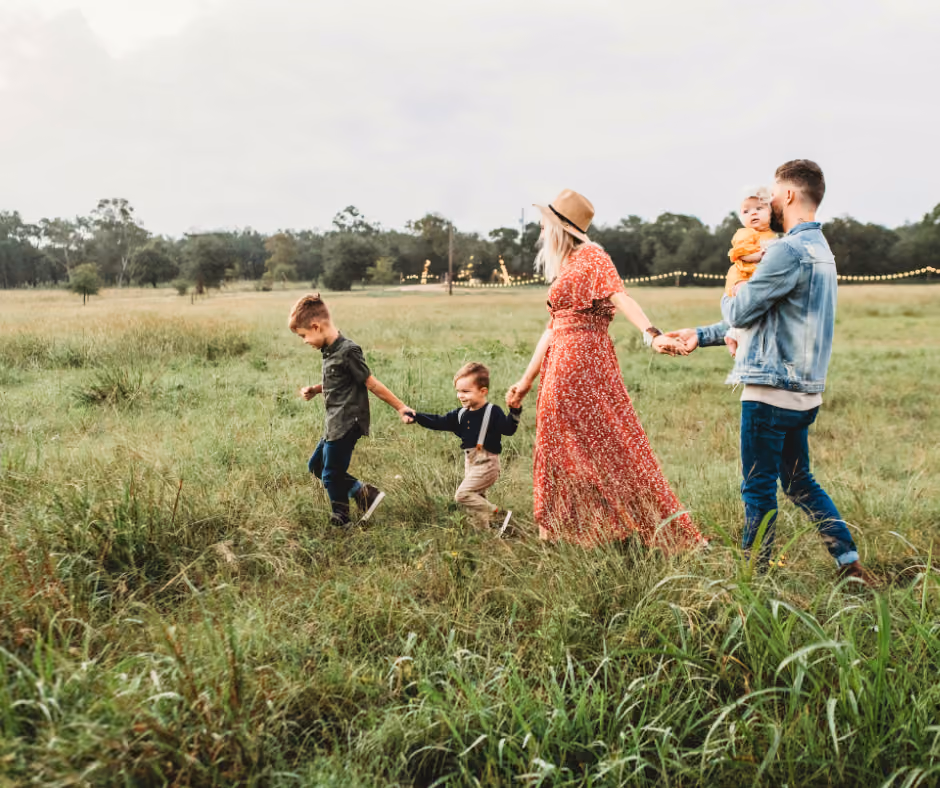 A family walking together through an open meadow at dusk.