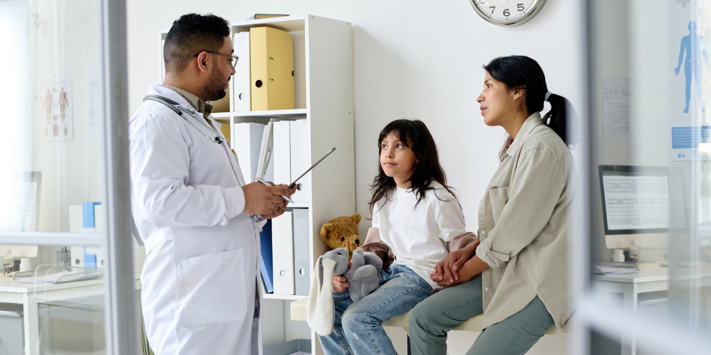 Mother with her daughter in an exam room listening to the doctor talk to them