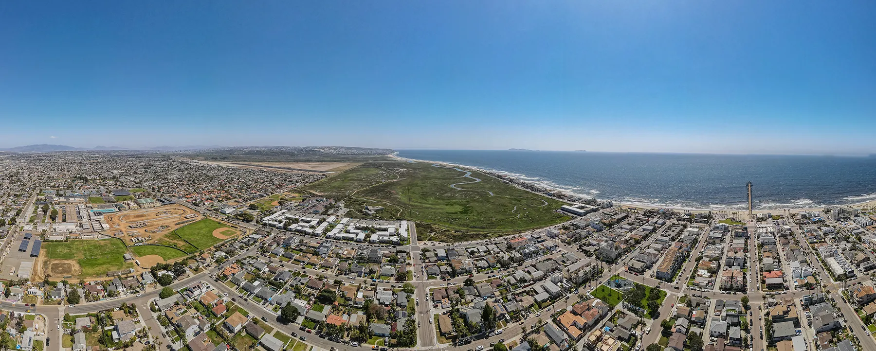 Wide aerial panorama of a coastal community stretching toward the ocean.