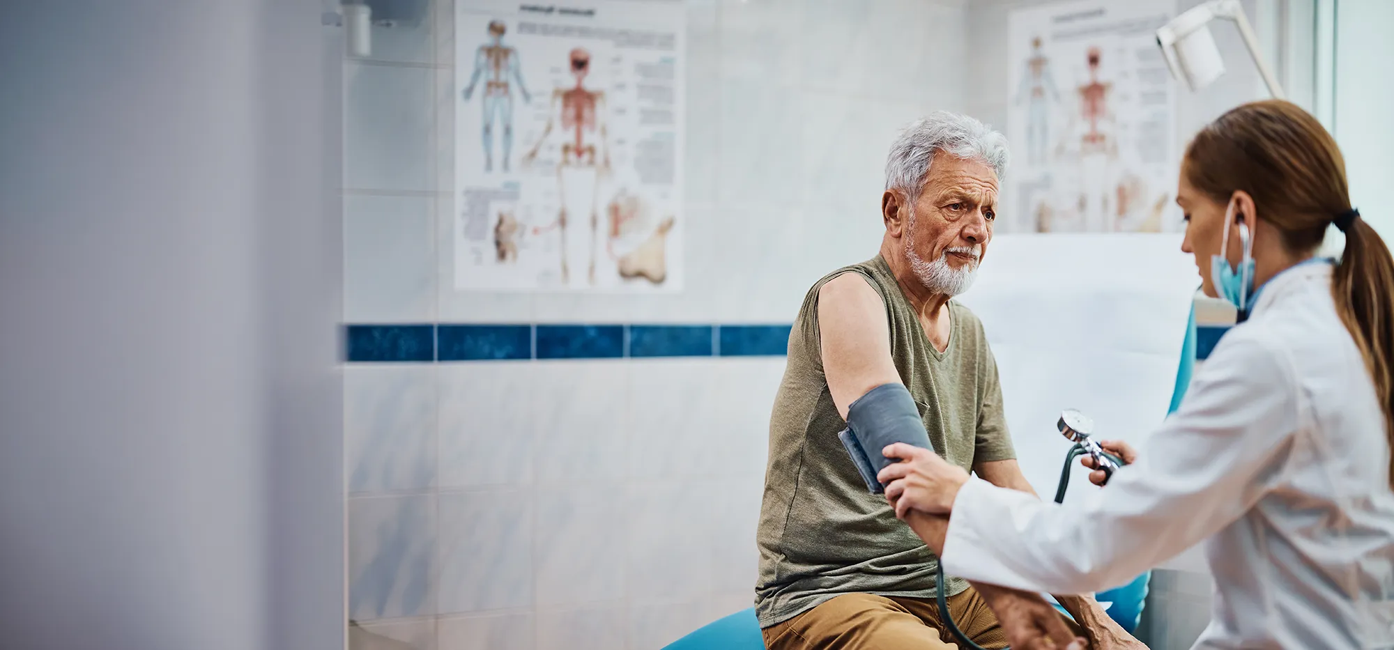 Healthcare professional checks an older man’s blood pressure during a clinic visit.