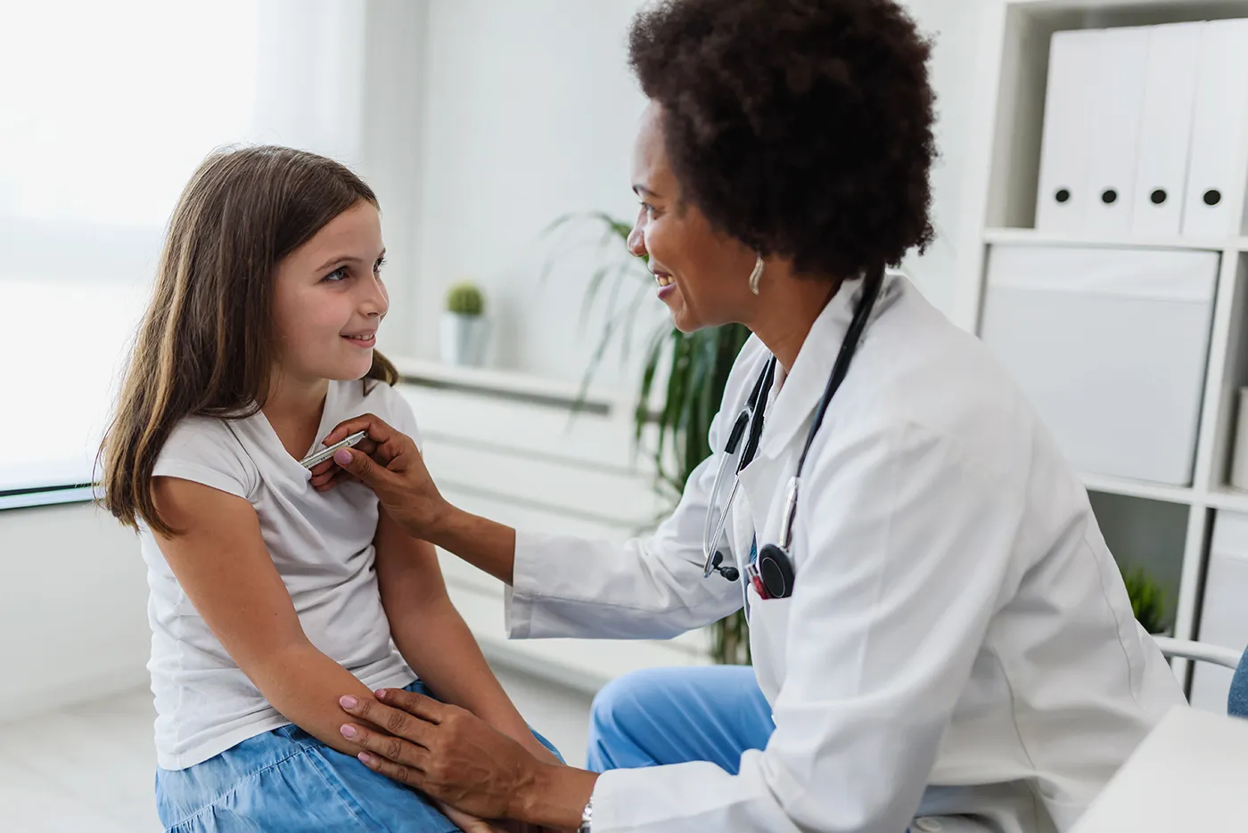Doctor uses a stethoscope to examine a young girl during a medical visit.