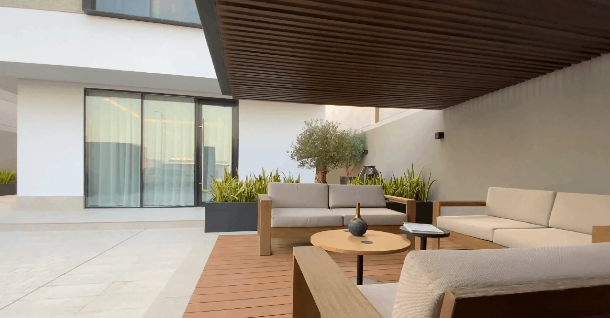Modern covered patio with cushioned seating and potted plants
