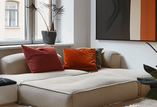 Light-colored sectional sofa with red and orange pillows
