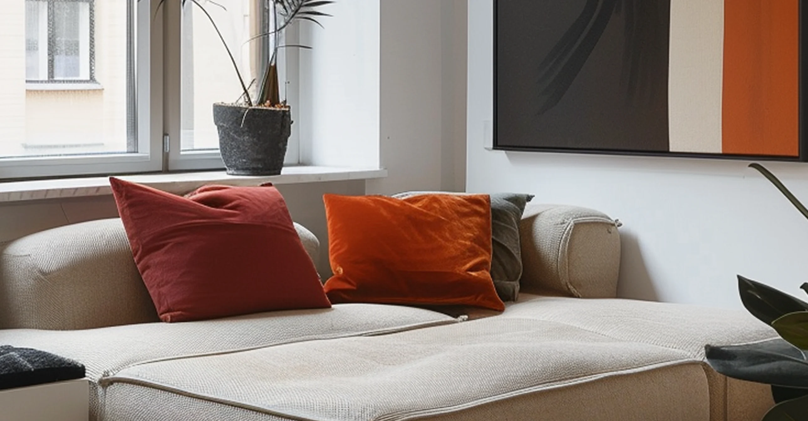 Light-colored sectional sofa with red and orange pillows