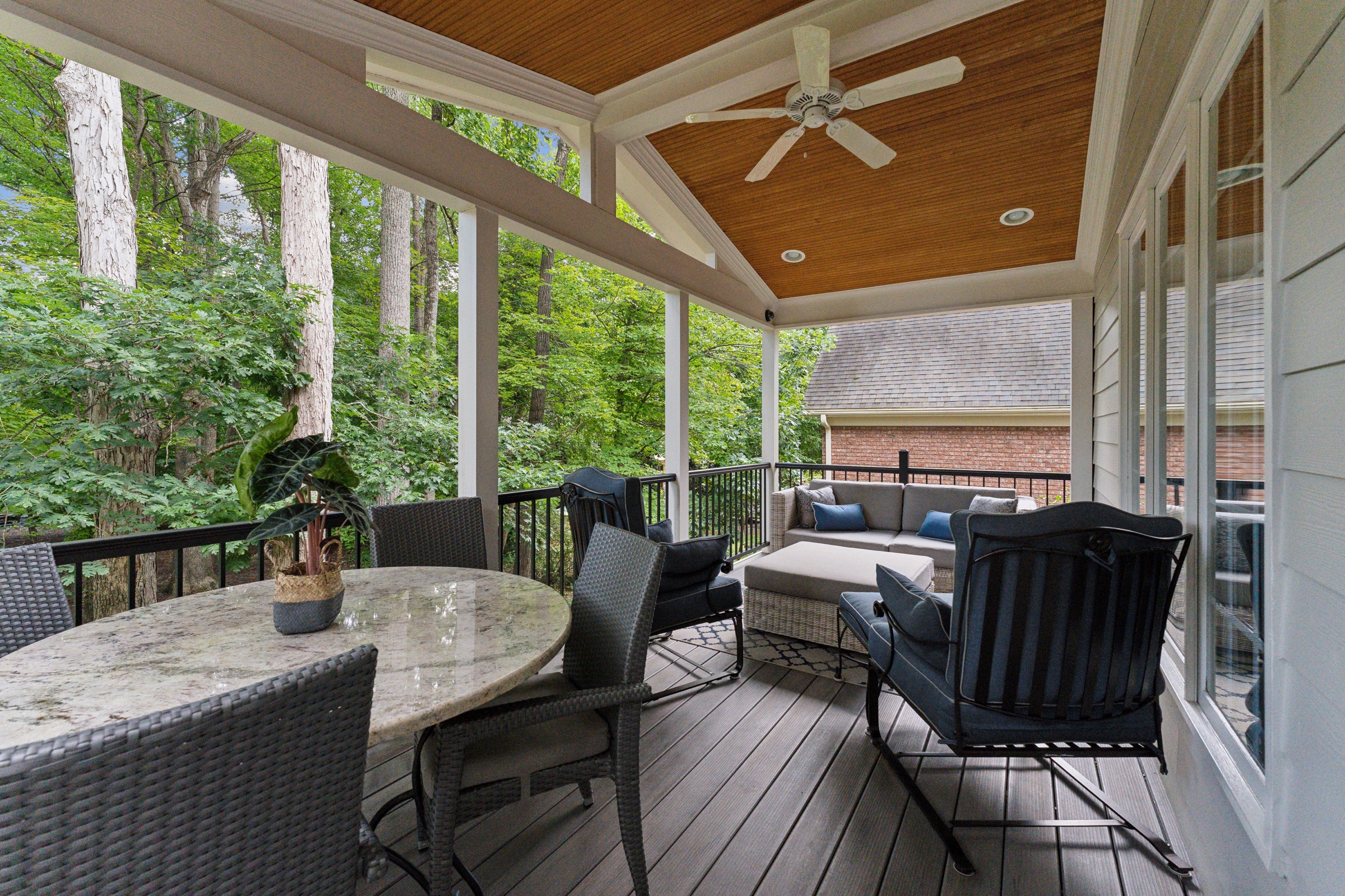 Covered outdoor living space overlooking a wooded setting
