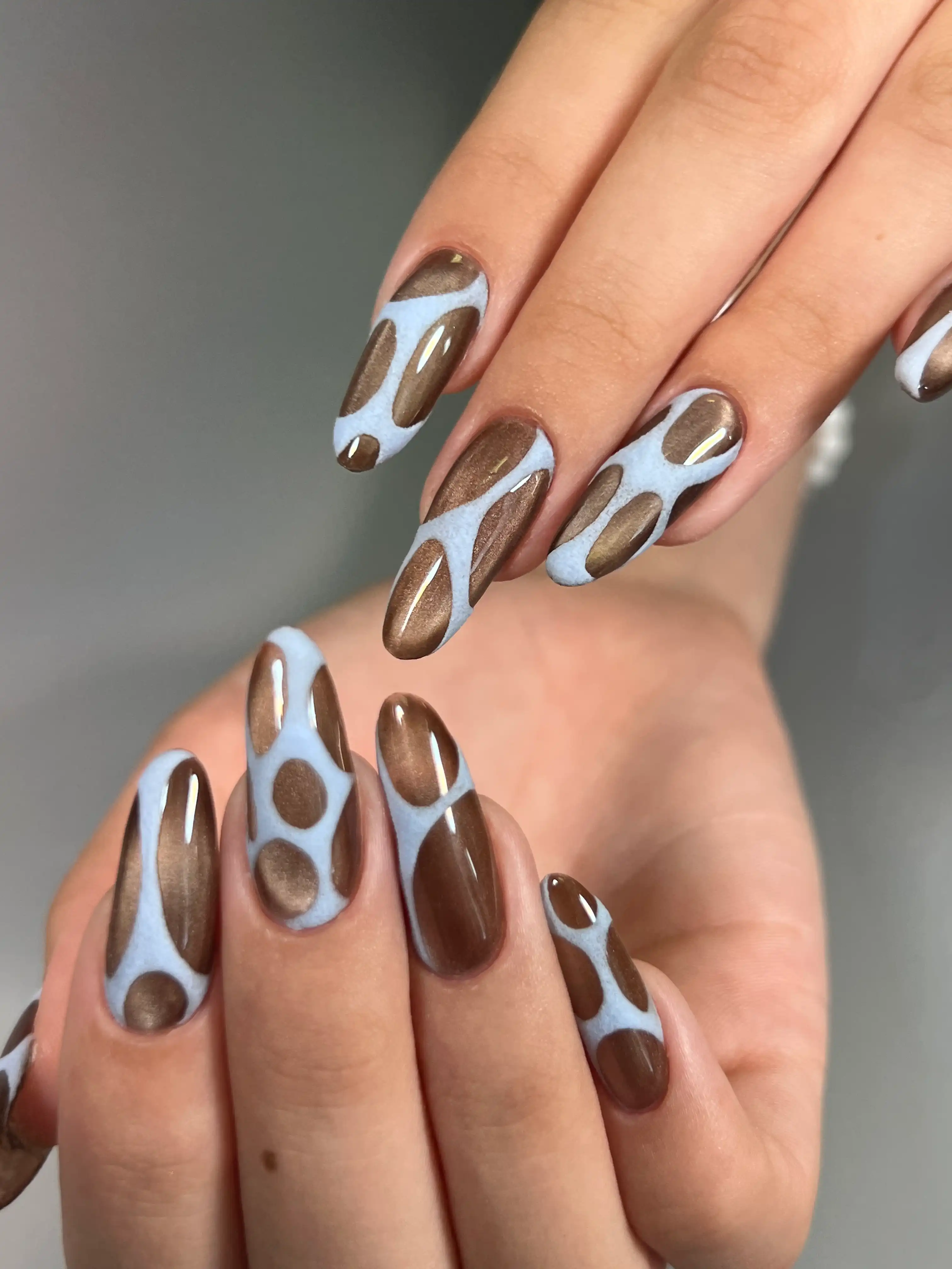 Braune Chromnägel mit hellblauem Wellenmuster als aufwendiges Nageldesign