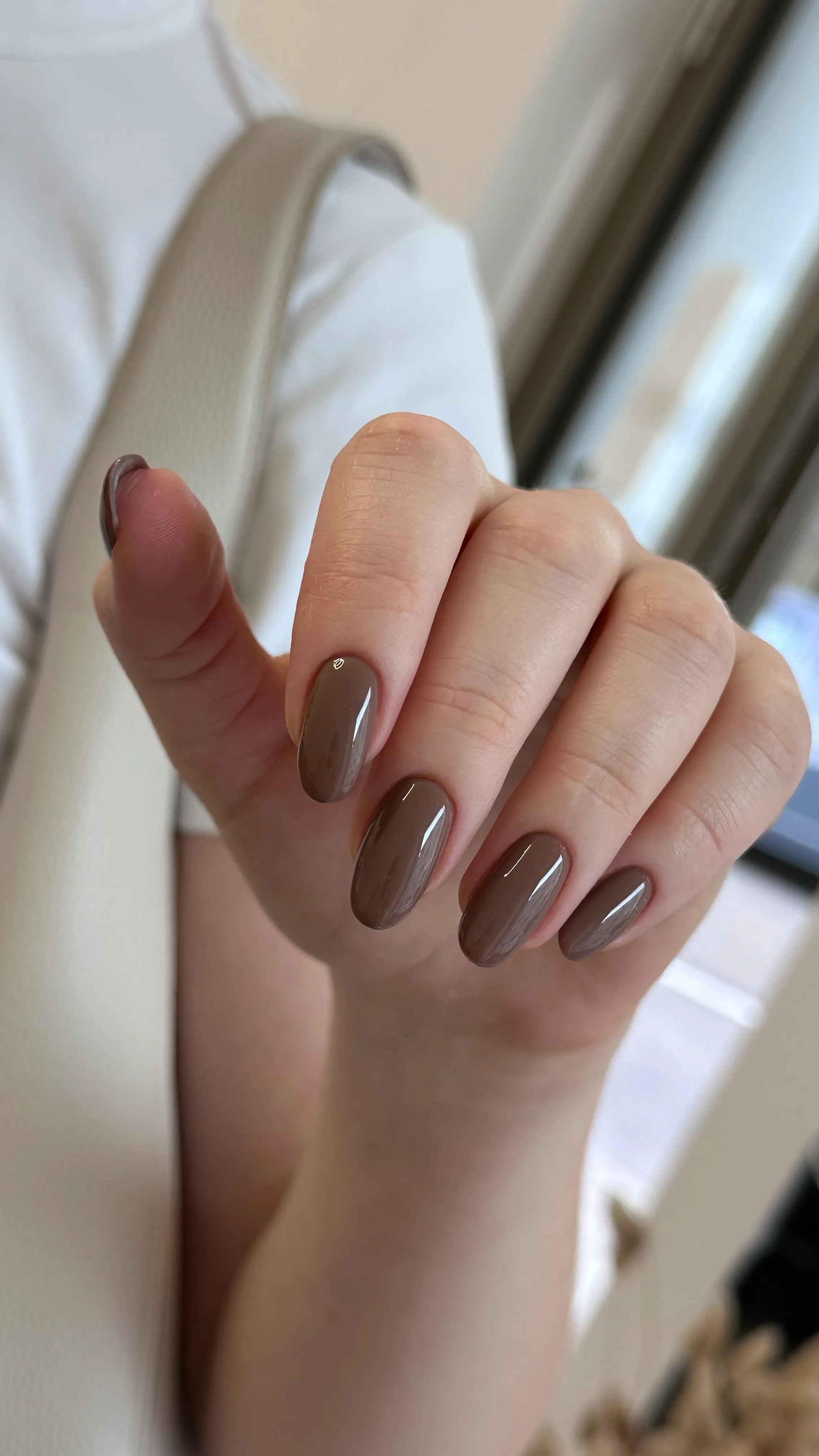 Ovale Gelnägel in glänzendem Taupe-Braun auf mittellangen Nägeln