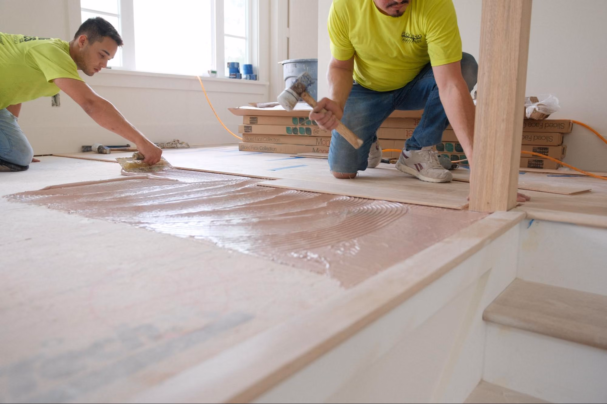 Professional flooring installer troweling adhesive during a flooring installation