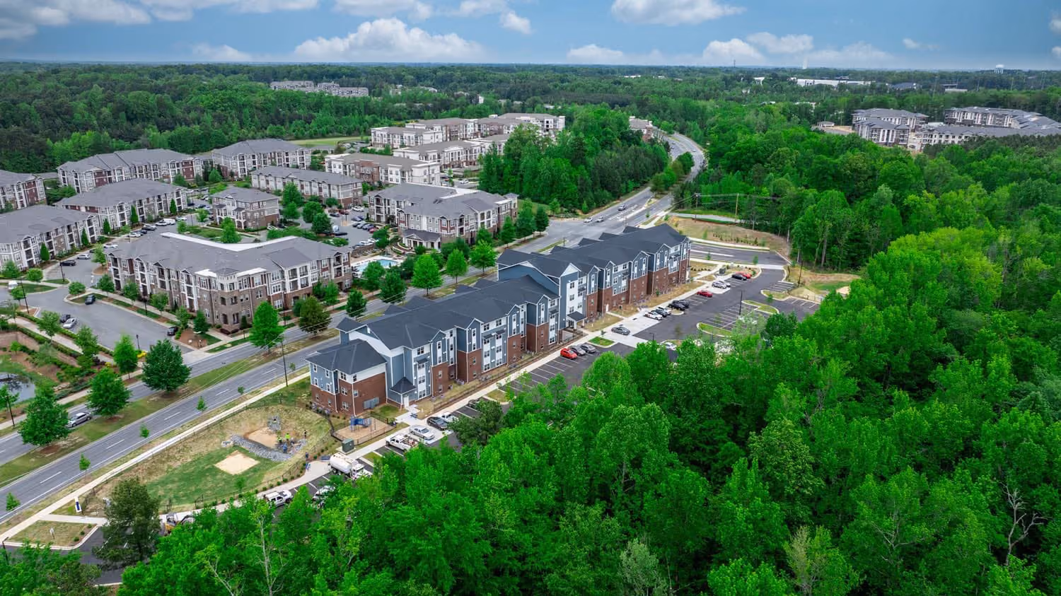 Aerial view of a multi-family apartment community with landscaped grounds