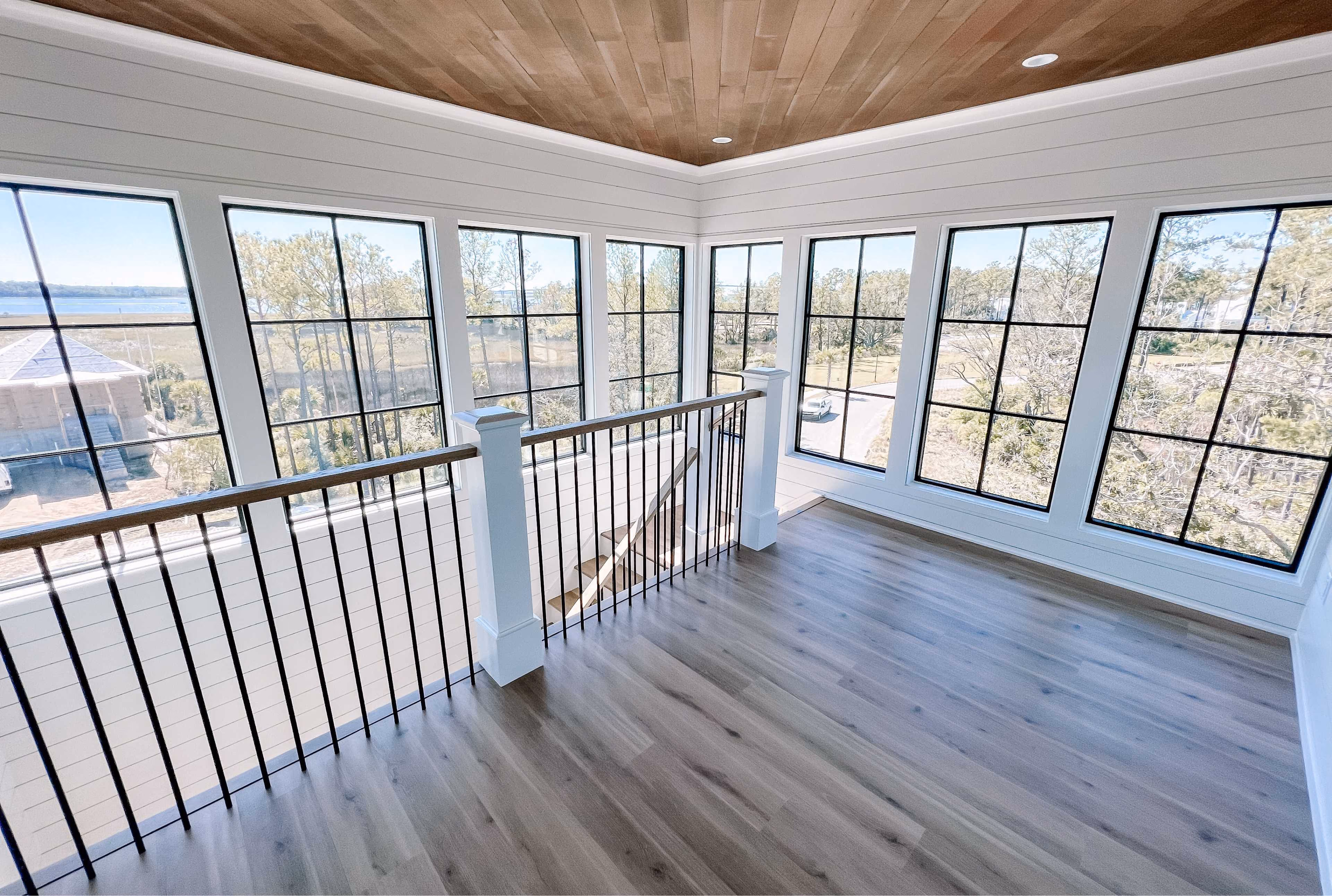 Upstairs landing with a stair railing and refinished hardwood flooring