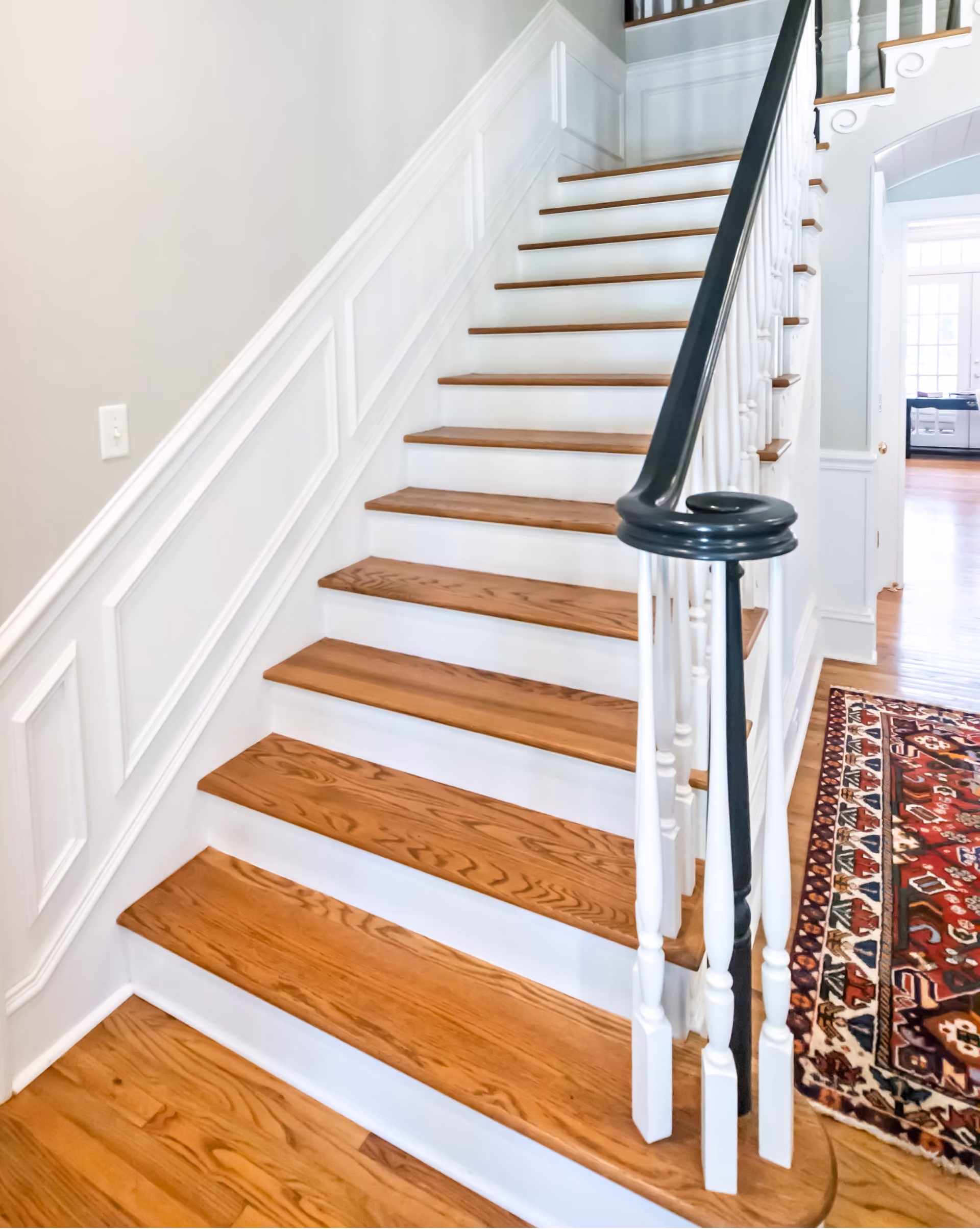 Staircase with refinished wood treads, white risers, and a patterned runner