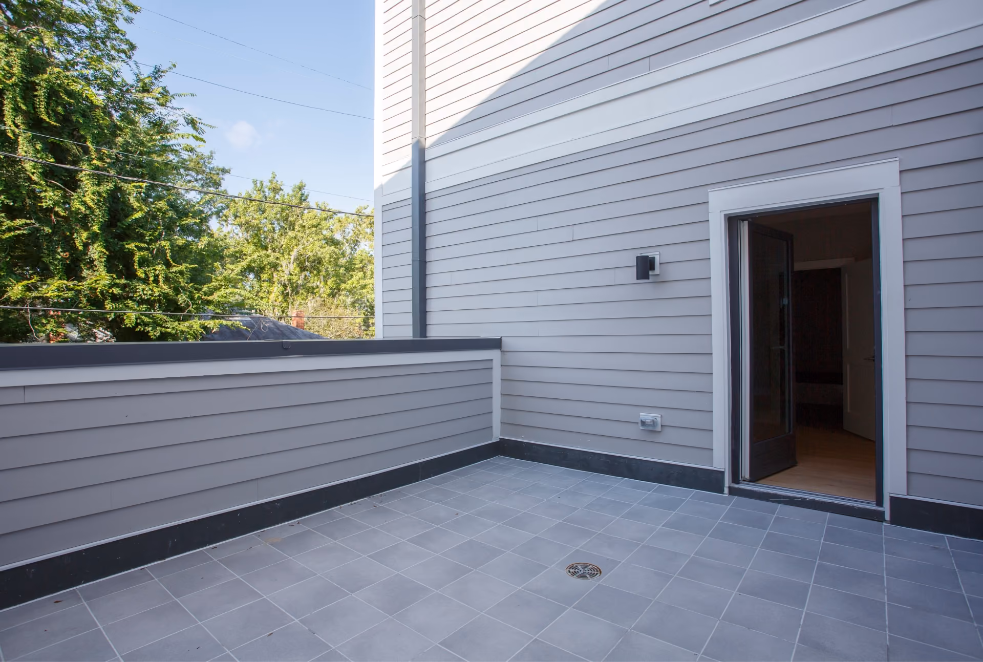 Rooftop deck with gray tile flooring along the exterior of a home
