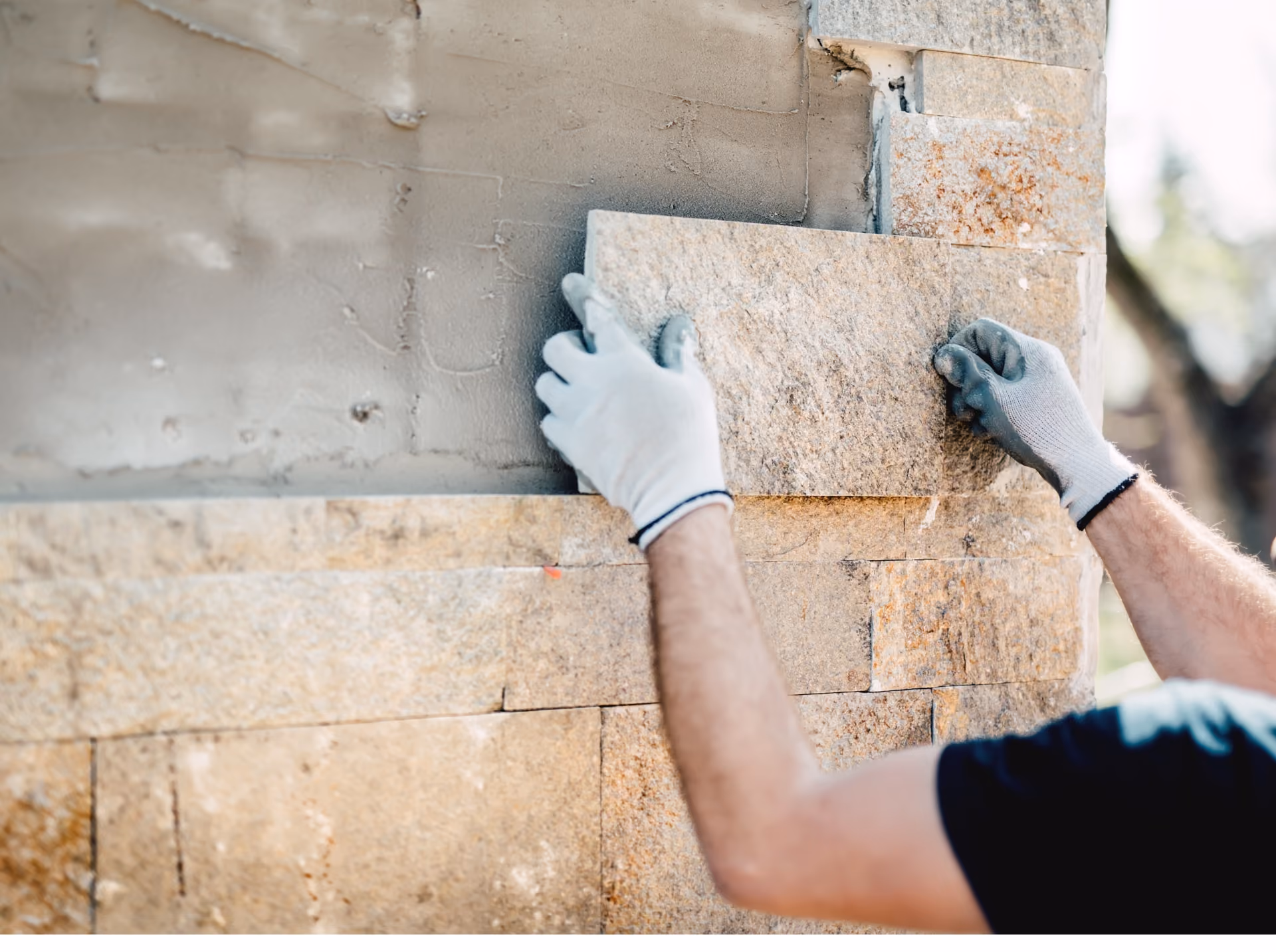 Installer setting large-format stone tile on an exterior wall