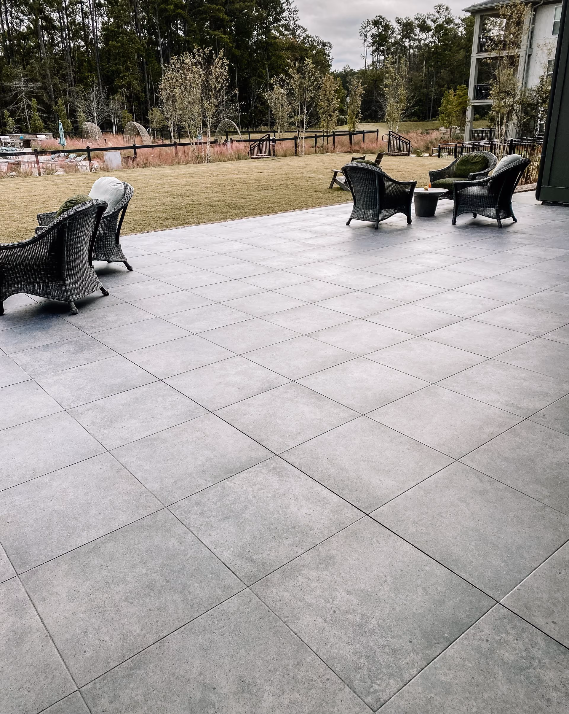 Outdoor patio with large-format gray tile flooring and wicker furniture