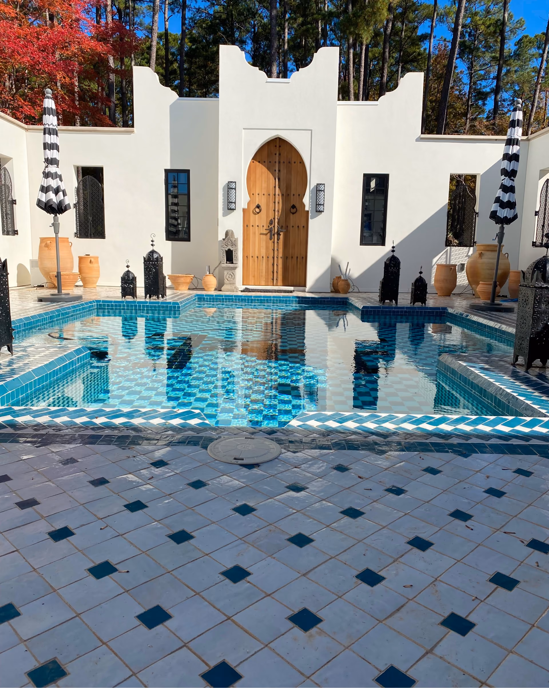 Pool deck with blue mosaic tile coping and gray tile flooring