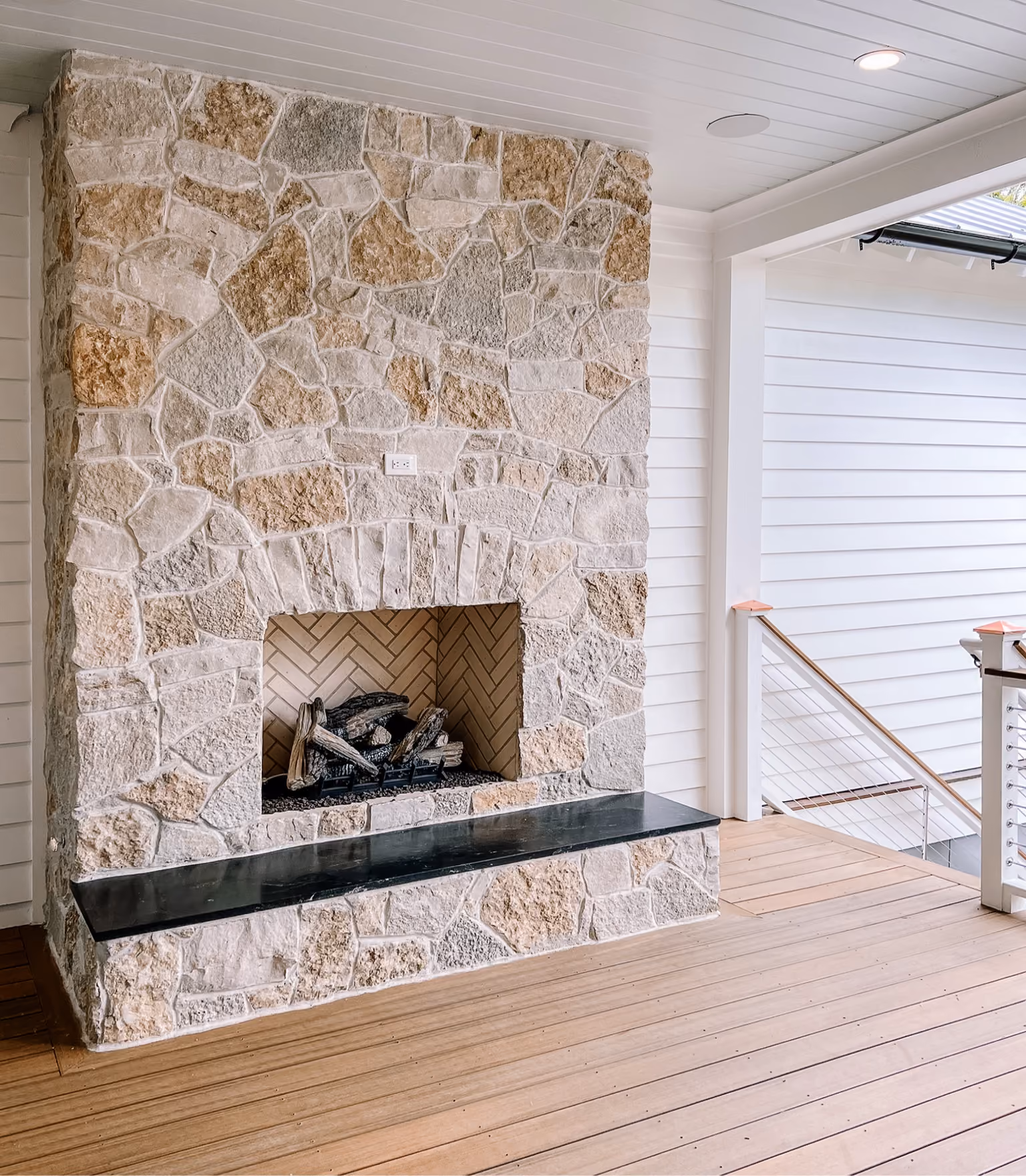 Natural stone accent wall with a herringbone stone hearth beside a staircase