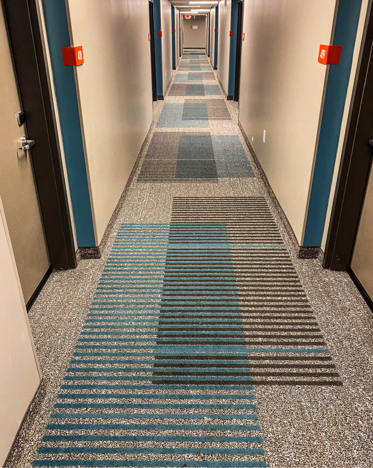 Hotel corridor with a terrazzo-look accent floor and patterned carpet runner